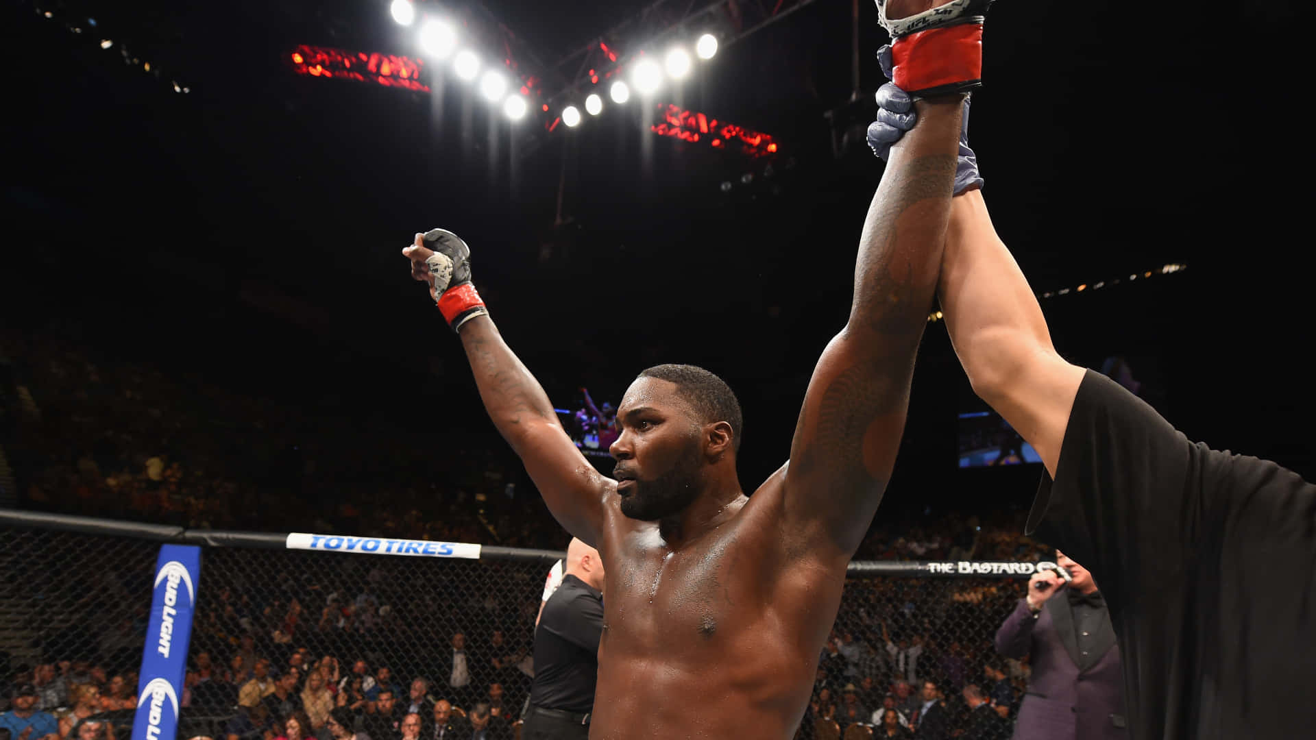 MMA 桌布 壁紙 — 一位勝利的混合武術家在明亮的競技場燈光下，在八角籠中高舉雙臂慶祝勝利，裁判舉起他的手。
