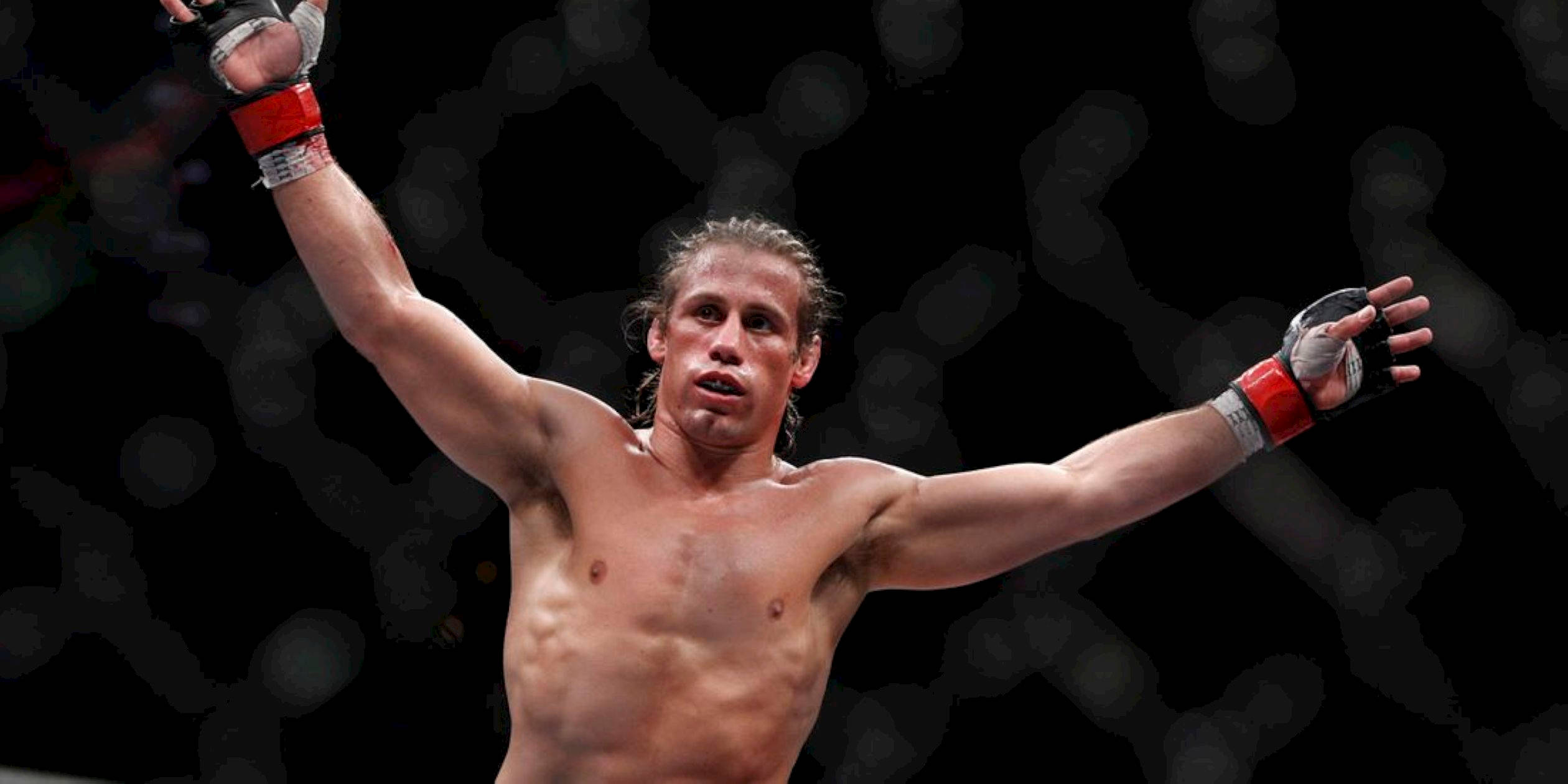 MMA 桌布 壁紙 — 一位勝利的混合武術家在昏暗的八角籠內高舉雙臂慶祝勝利，背景是模糊的籠網。