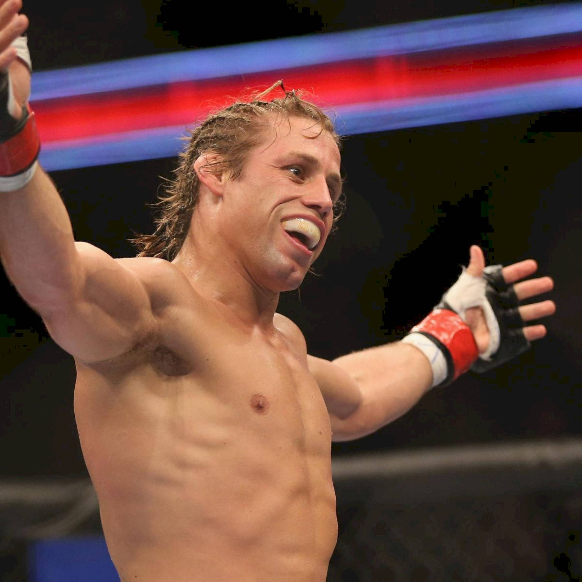 MMA 桌布 壁紙 — 一位勝利的混合武術家在燈光明亮的八角籠中高舉雙臂慶祝。