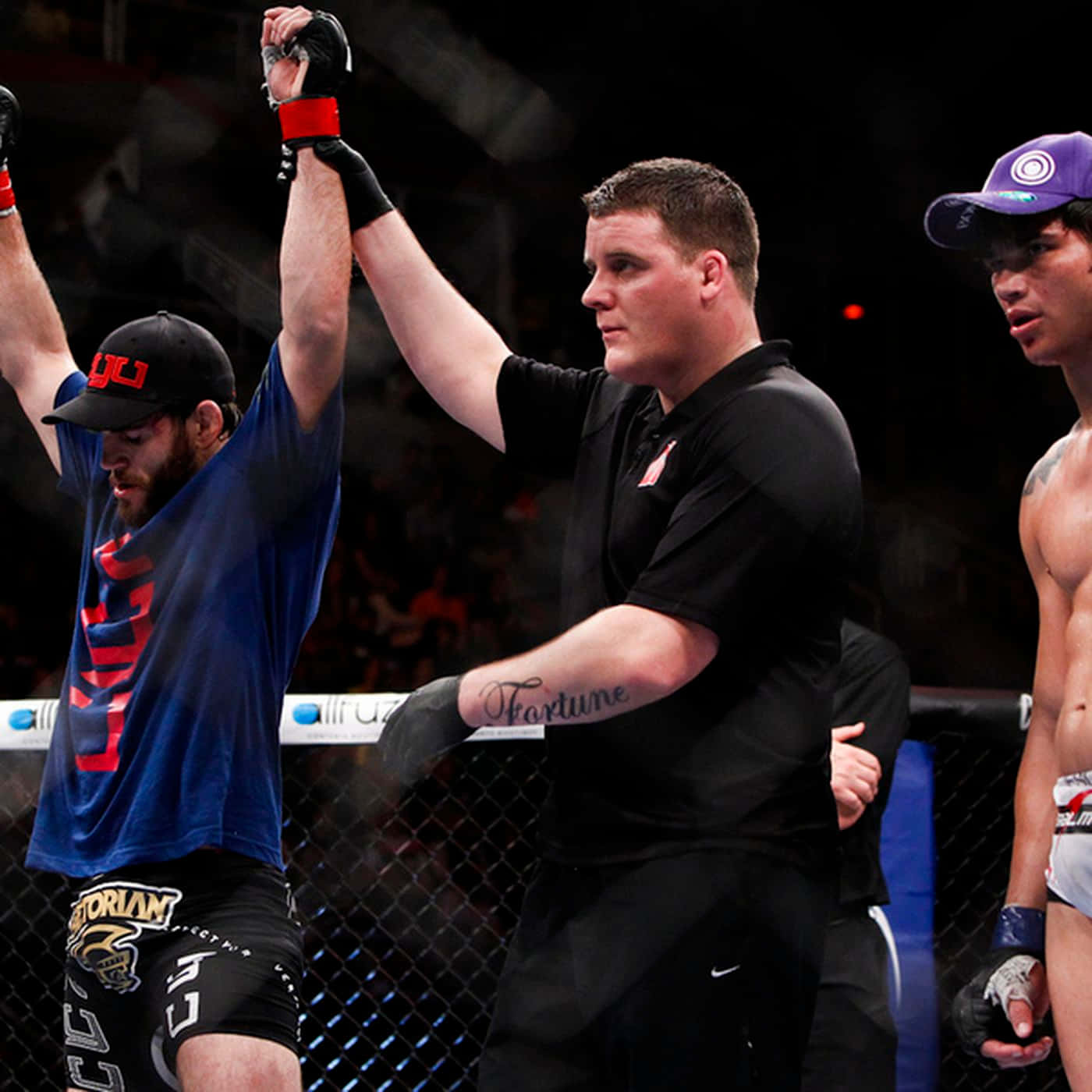 UFC 桌布 壁紙 — 一位勝利的混合武術家舉起手臂，裁判在UFC八角籠內宣佈他為勝者。