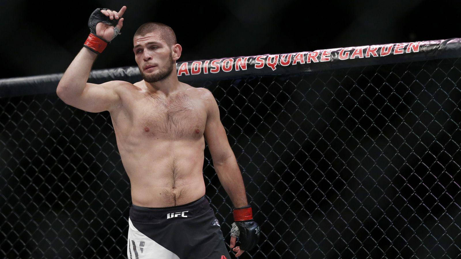 UFC 桌布 壁紙 — 一位勝利的混合武術選手在麥迪遜廣場花園的UFC八角籠內，在明亮的場館燈光下舉起拳頭。
