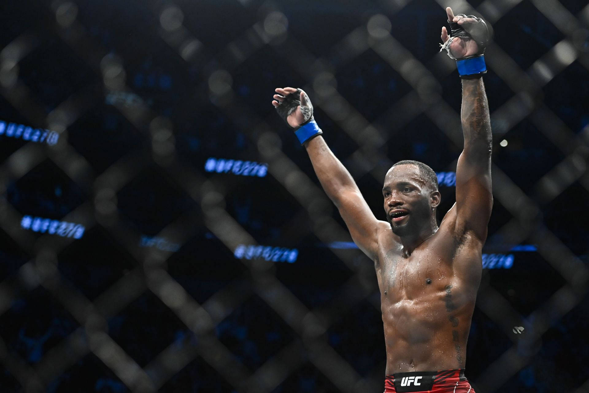 MMA 桌布 壁紙 — 一位勝利的綜合格鬥家在明亮的競技場燈光下，於UFC八角籠內高舉雙臂慶祝勝利。