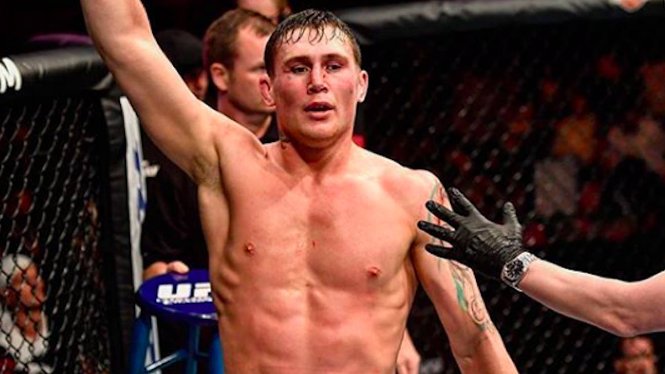 UFC 桌布 壁紙 — 一位勝利的綜合格鬥選手在UFC八角籠內高舉手臂慶祝勝利，裁判的手放在他的肩膀上。