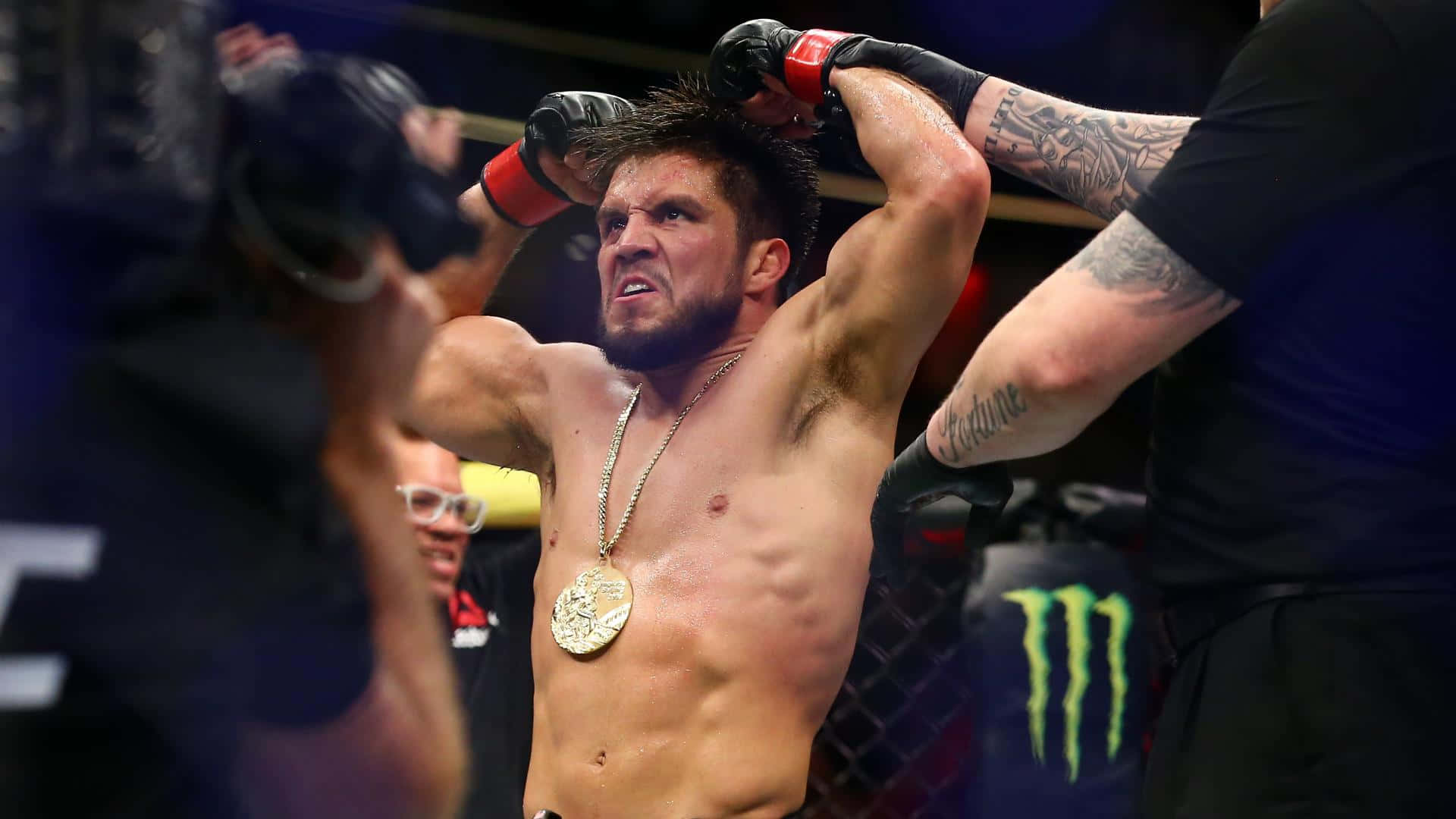 UFC 桌布 壁紙 — 一位勝利的綜合格鬥選手在八角籠中戴上金牌冠軍獎牌，勝利地高舉雙臂。