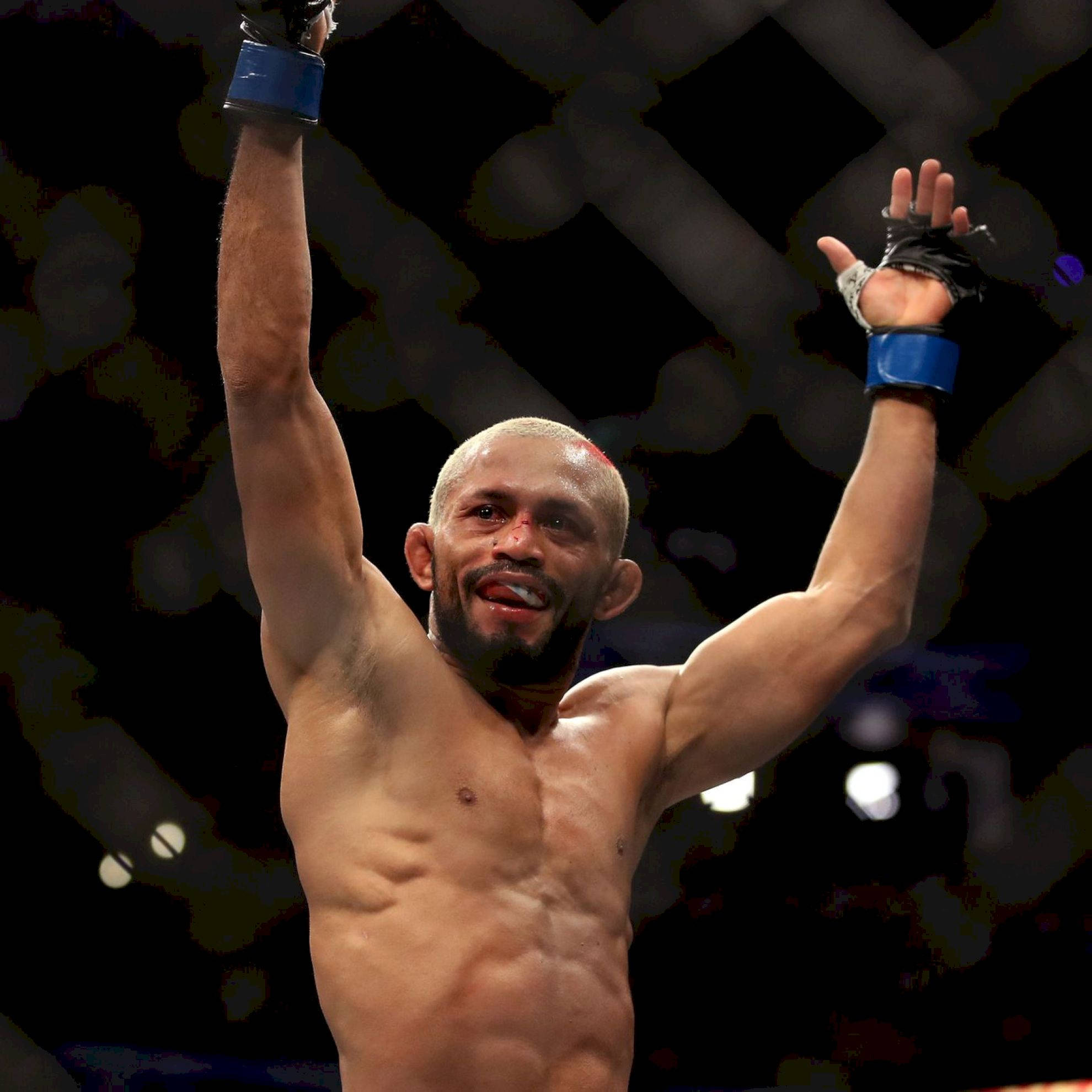 MMA 桌布 壁紙 — 一位勝利的綜合格鬥選手在昏暗的八角籠內高舉雙臂，身後有模糊的燈光。