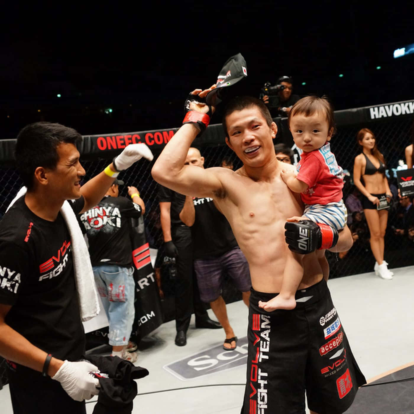 martial arts 桌布 壁紙 — 一位勝利的綜合格鬥選手在比賽結束後於八角籠中抱著他的寶寶，露出燦爛的笑容。