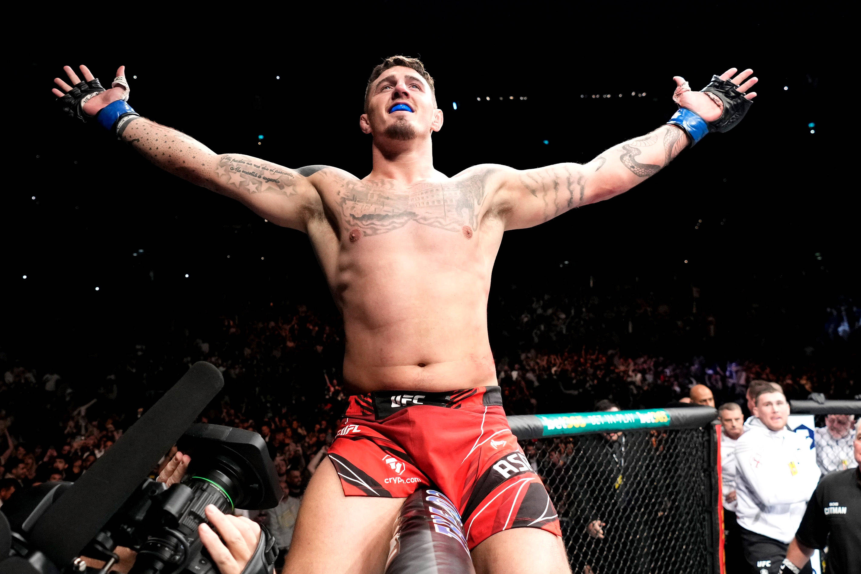 UFC 桌布 壁紙 — 一位勝利的綜合格鬥選手在燈光明亮的八角籠中高舉雙臂慶祝，周圍是歡呼的粉絲。