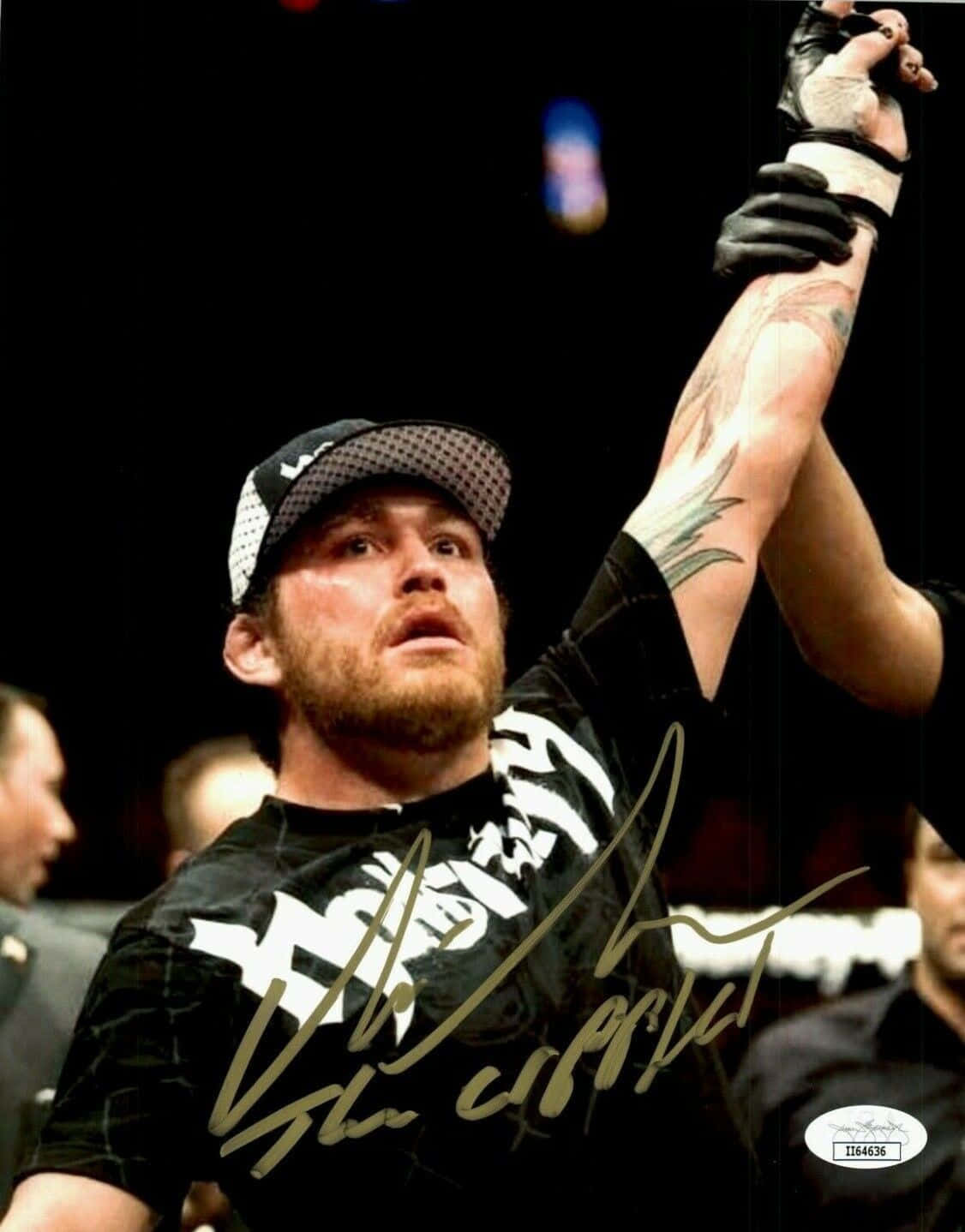 UFC 桌布 壁紙 — 一位勝利的綜合格鬥選手在燈光昏暗的競技場內高舉戴著手套的手慶祝勝利。