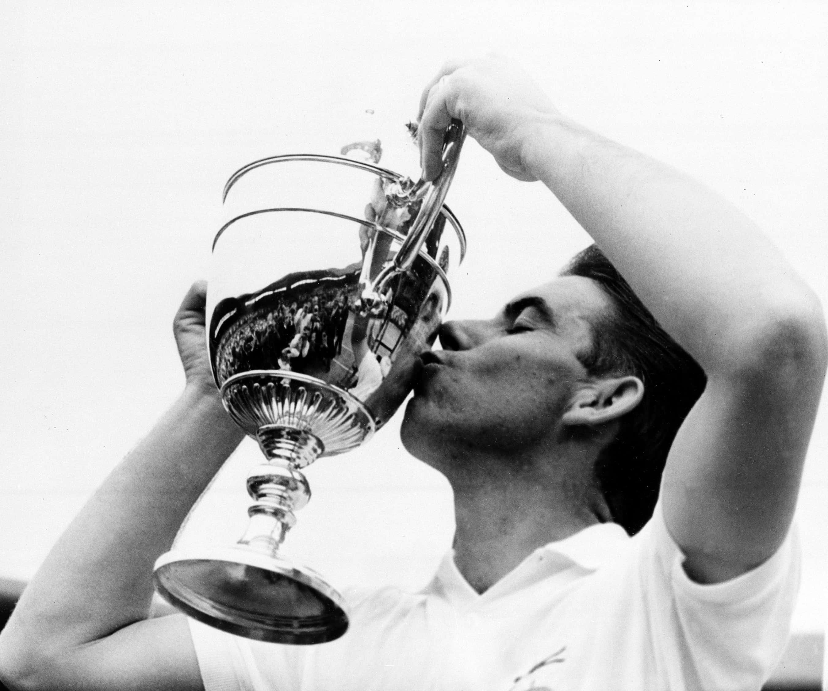 Tennis 桌布 壁紙 — 一位勝利的運動員在經典的黑白體育勝利時刻親吻閃亮的銀色獎盃。