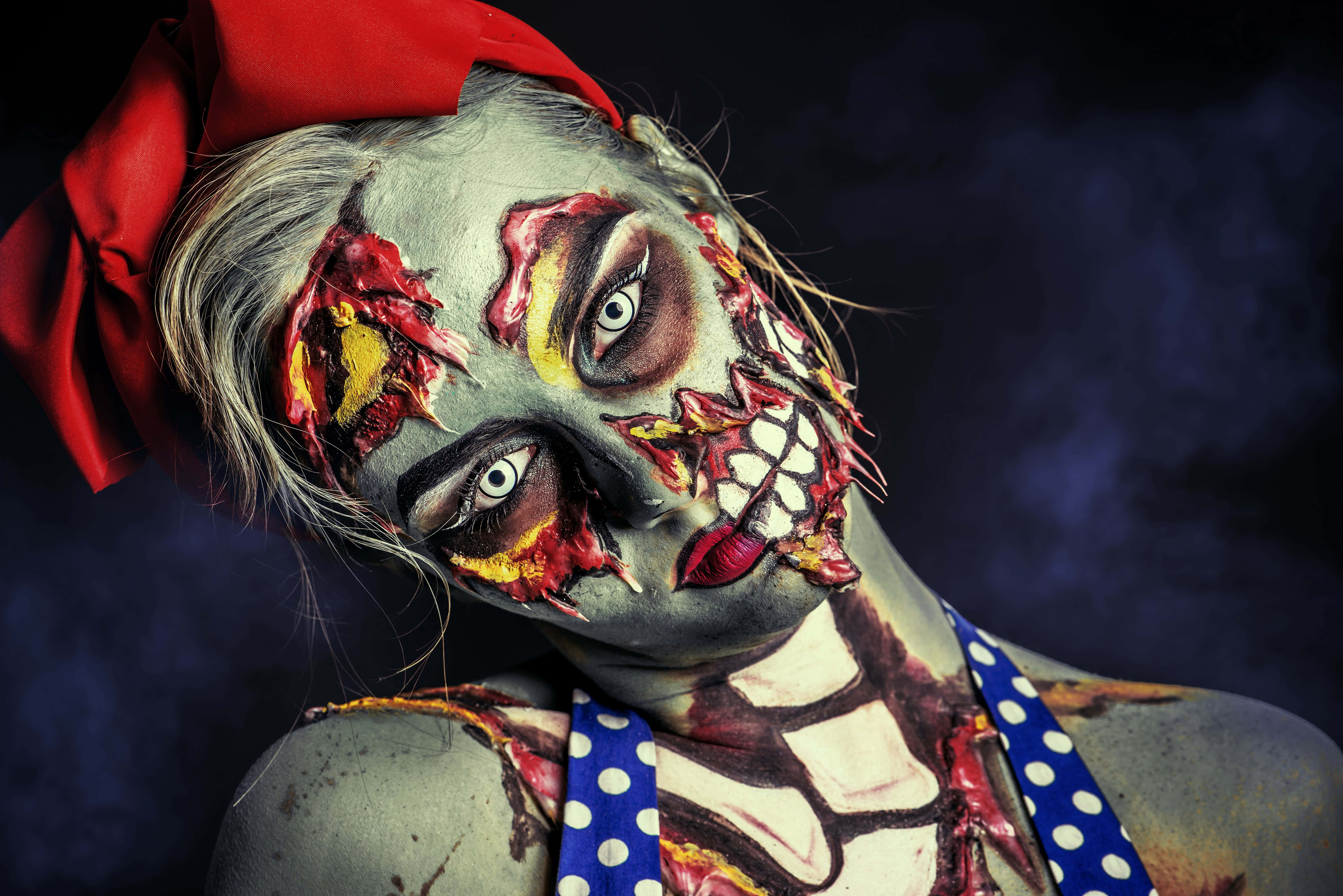Halloween Makeup 桌布 壁紙 — 一位化著殭屍妝、戴著紅色蝴蝶結的女性，在黑暗煙霧繚繞的背景中凝視著。