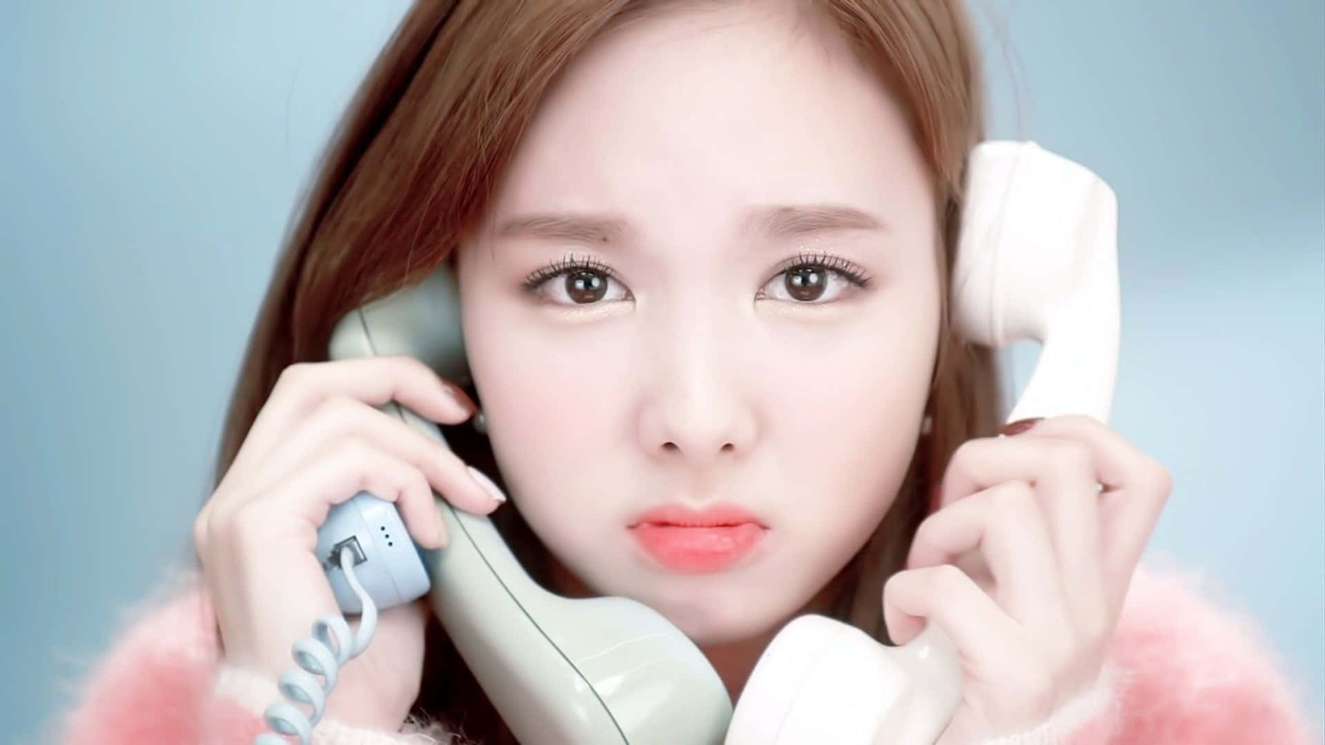 Phone Call 桌布 壁紙 — 一位化著淡妝的年輕女性，在淡藍色背景前將復古電話聽筒貼在耳邊。