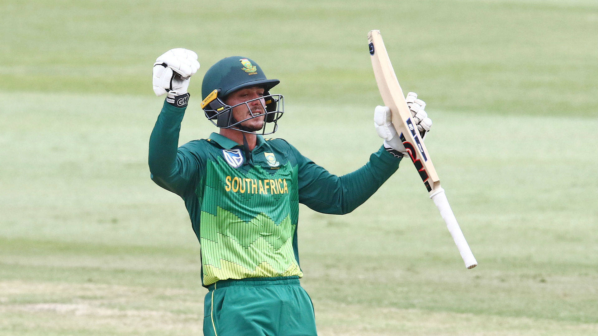 quinton de kock 桌布 壁紙 — 一位南非板球運動員在草地上高舉球棒慶祝勝利。