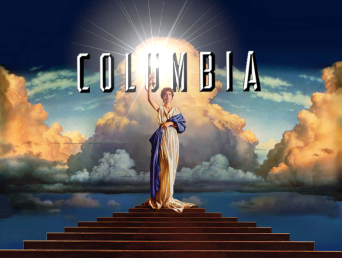 電影 桌布 壁紙 — 一位古典女神站在階梯頂端，在燦爛的陽光下，上方有「COLUMBIA」字樣，背景是戲劇性的多雲天空。