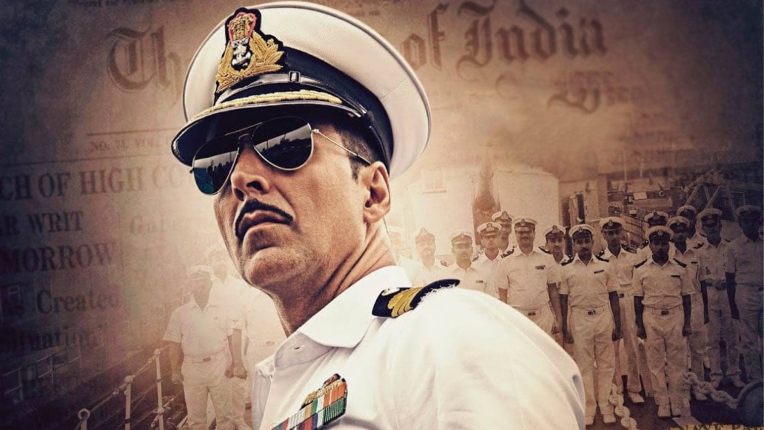 Akshay Kumar 桌布 壁紙 — 一位嚴肅的海軍軍官身穿白色制服和太陽眼鏡，站在船員和復古報紙頭條的背景前。