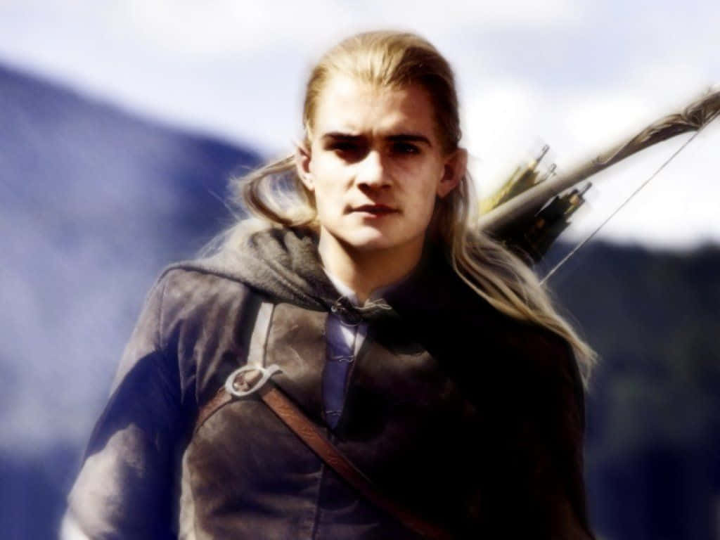 legolas 桌布 壁紙 — 一位嚴肅的精靈，長長的金髮和弓，站在霧氣繚繞的山景中，天空多雲。