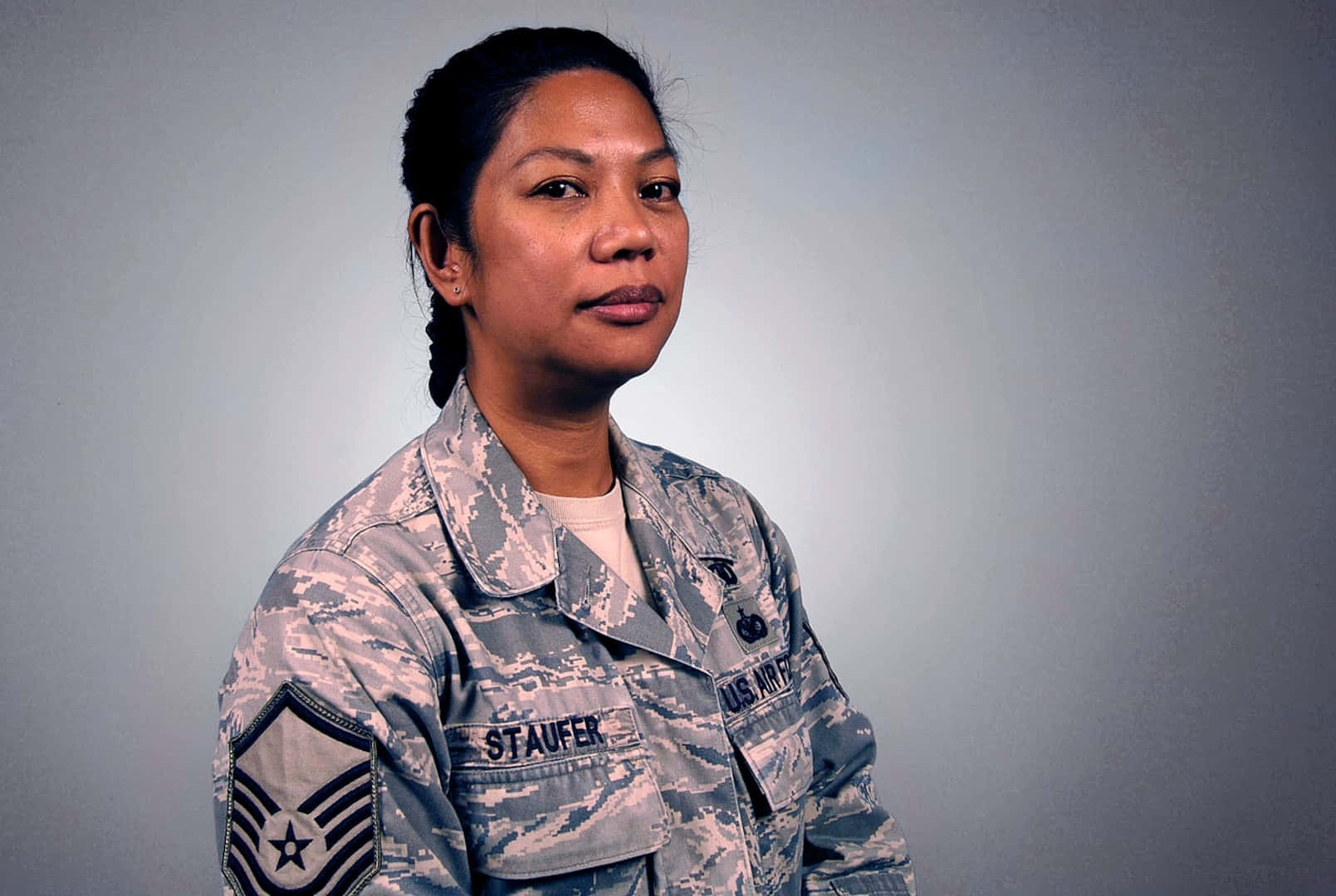 空軍 桌布 壁紙 — 一位嚴肅的美國空軍女軍士身穿迷彩制服，在純灰色攝影棚背景前擺姿勢。