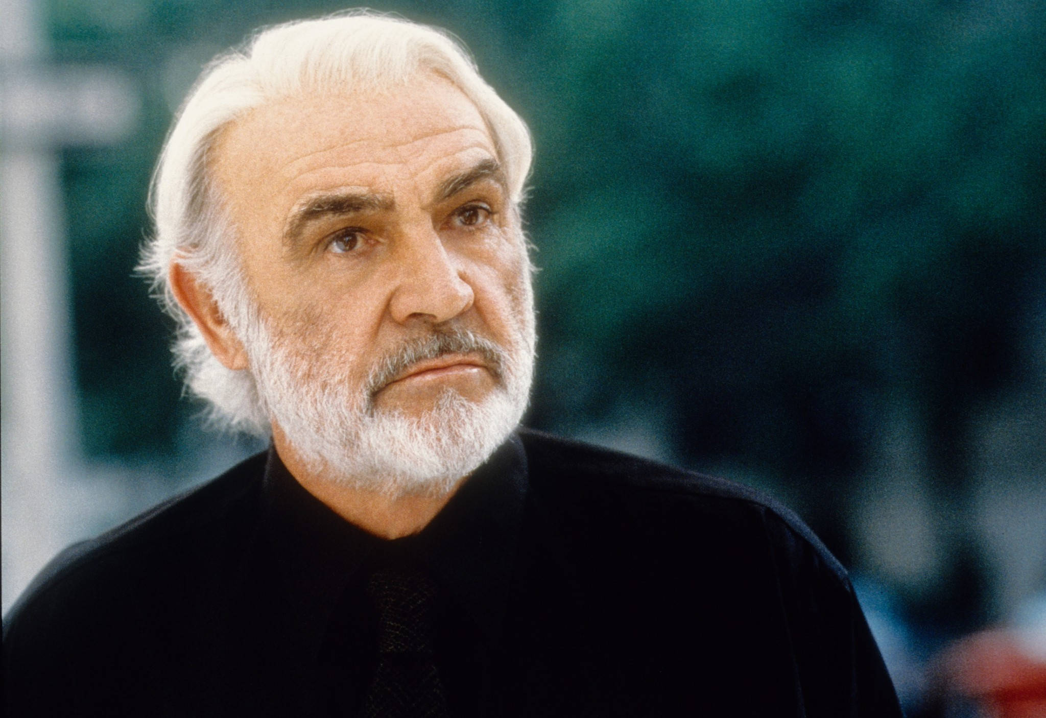 Sean Connery 桌布 壁紙 — 一位嚴肅的老年男子特寫肖像，白髮白鬍鬚，身穿黑色襯衫，背景為模糊的綠色。