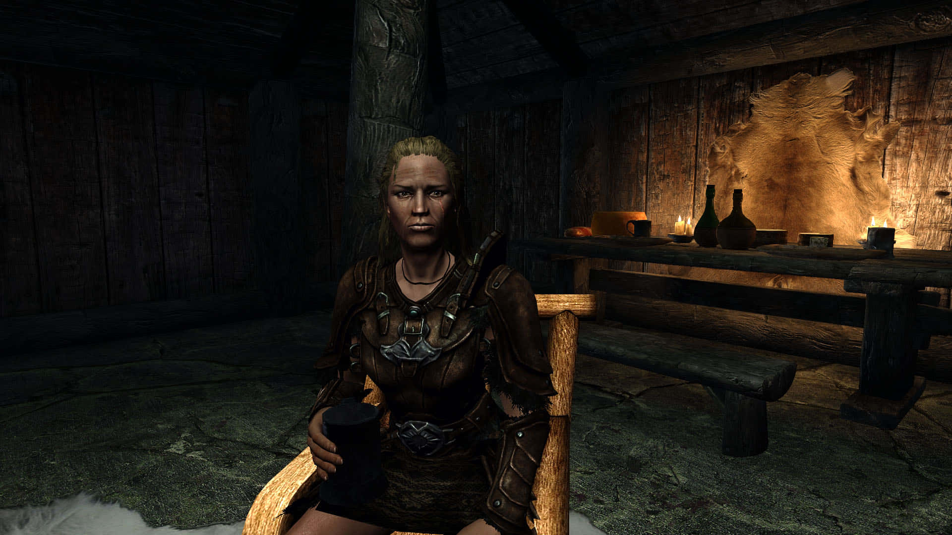 Skyrim Delphine 桌布 壁紙 — 一位嚴肅的裝甲女性坐在燭光照亮的昏暗木屋中，身後牆上掛著毛皮。