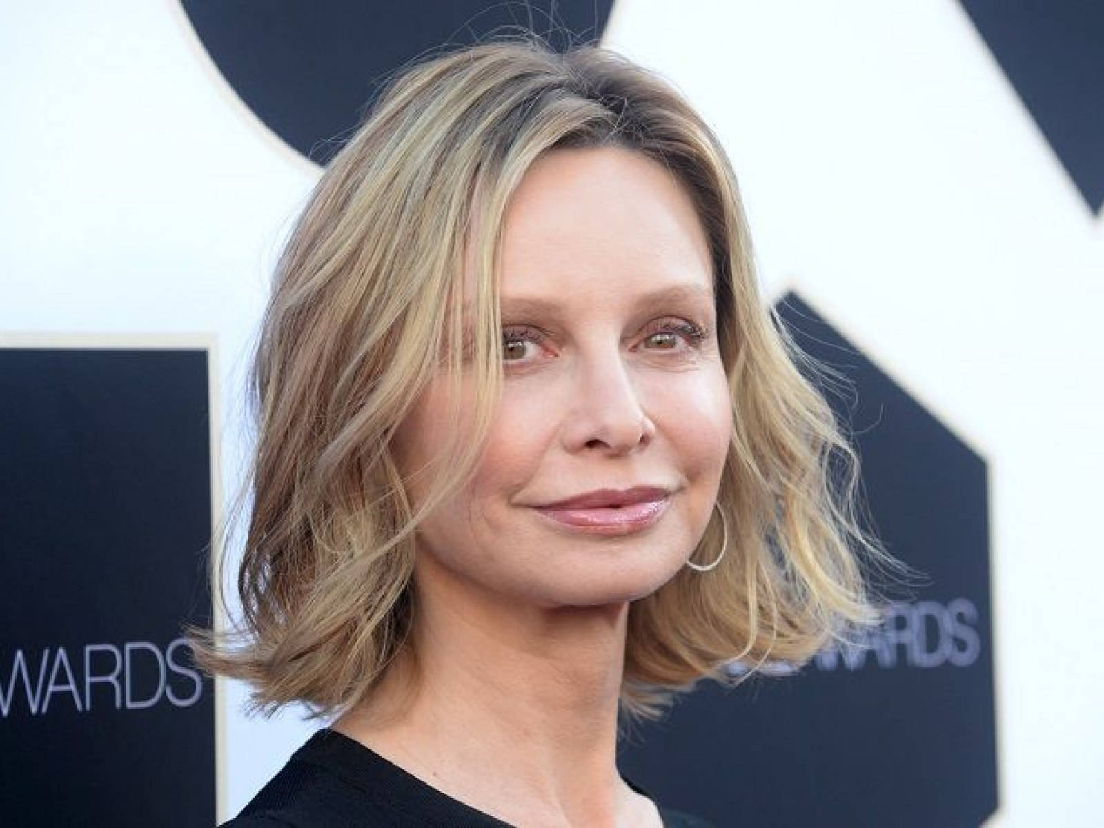 Celebrity 桌布 壁紙 — 一位在頒獎活動中留著波浪金髮和戴著圈圈耳環的女子的特寫肖像。