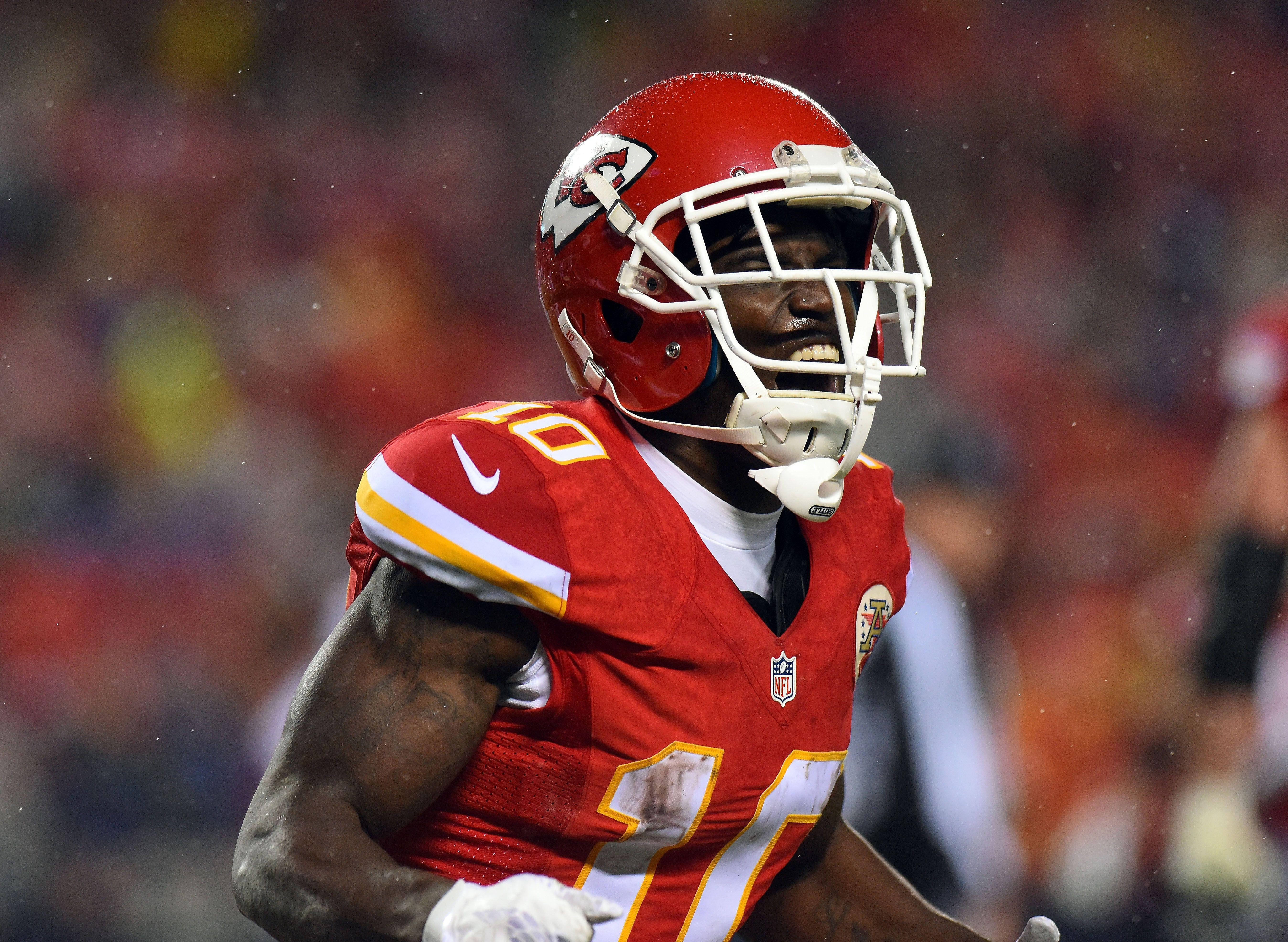 Tyreek Hill 桌布 壁紙 — 一位堅定的NFL美式足球員，戴著紅色頭盔、穿著紅色球衣，在雨中穿過體育場的人群。