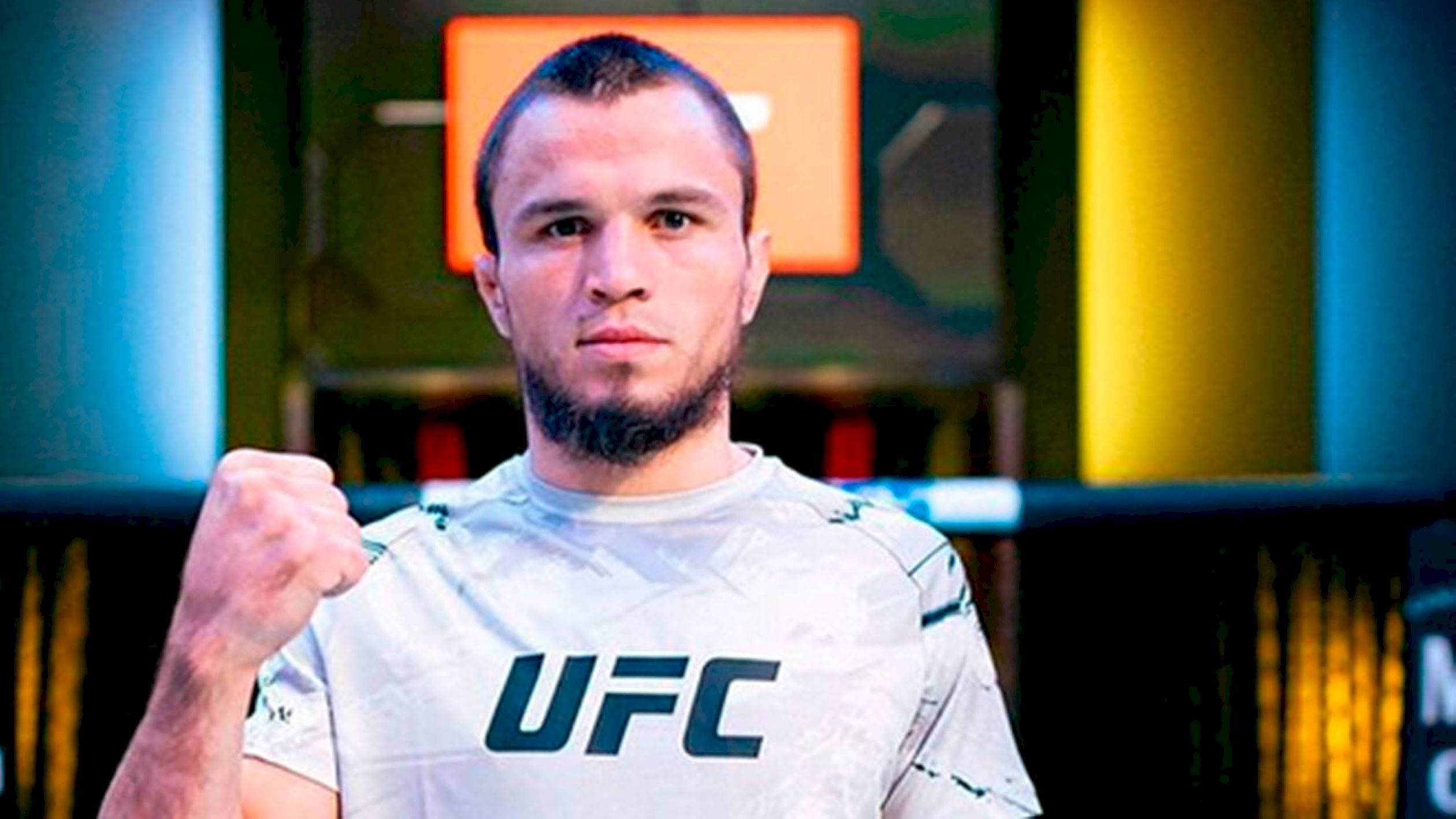 UFC 桌布 壁紙 — 一位堅定的UFC拳手在燈光明亮的競技場中，緊握拳頭，凝視著鏡頭。