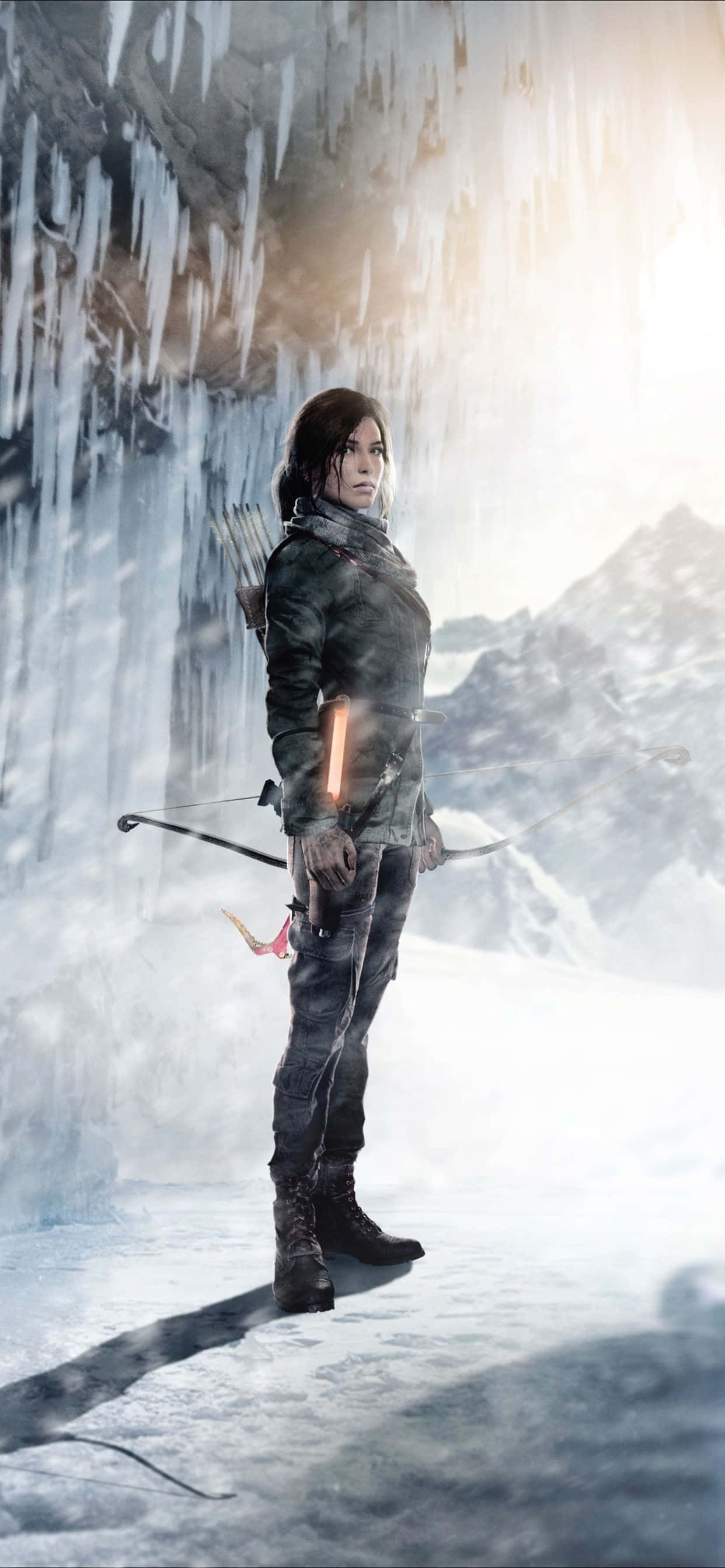 iPhone Xs Max Rise Of The Tomb Raider 桌布 壁紙 — 一位堅定的女弓箭手站在冰凍的山洞中，冰柱懸掛在她上方，背景是白雪覆蓋的山峰。