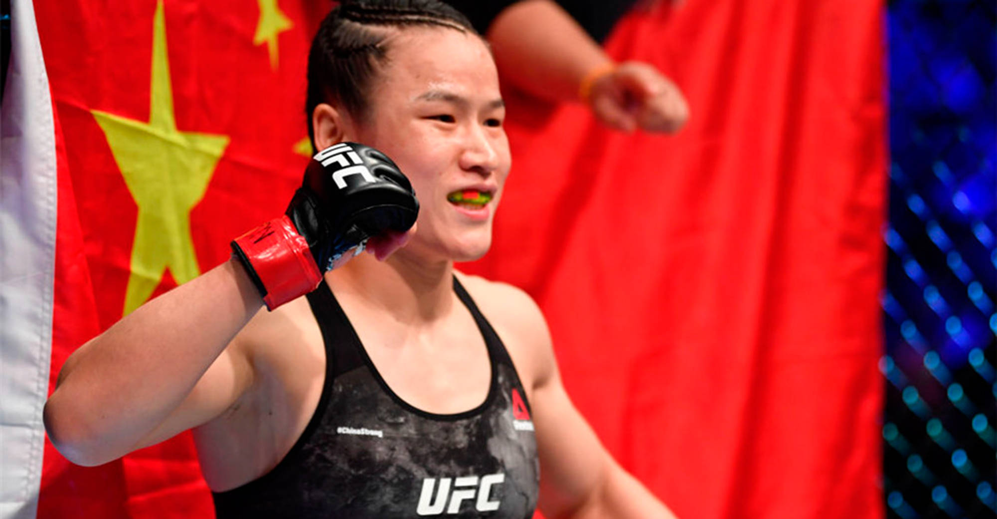 運動 桌布 壁紙 — 一位堅定的女性MMA拳手身穿UFC緊身衣，在紅色中國國旗背景下勝利地舉起戴手套的拳頭。