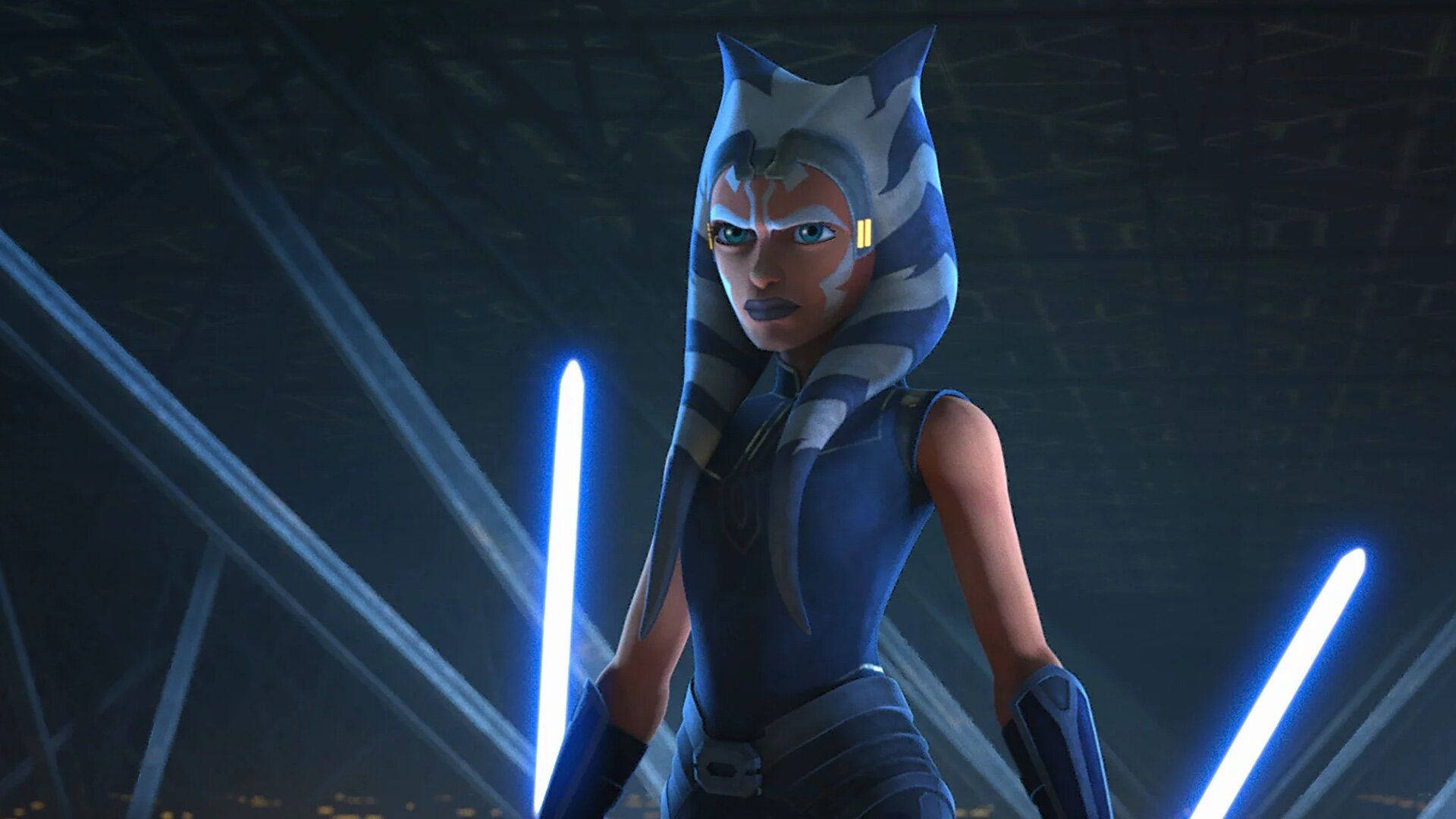 Ahsoka Tano 桌布 壁紙 — 一位堅定的女性絕地武士手持藍色光劍，站在黑暗的未來競技場中，沐浴在發光的光束下。
