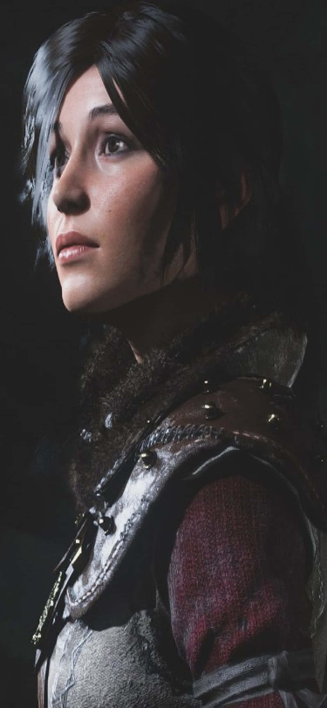 iPhone X Shadow Of The Tomb Raider 桌布 壁紙 — 一位堅定的女戰士身穿精細鎧甲並飾有毛皮邊，在黑暗背景下向上凝視的特寫。