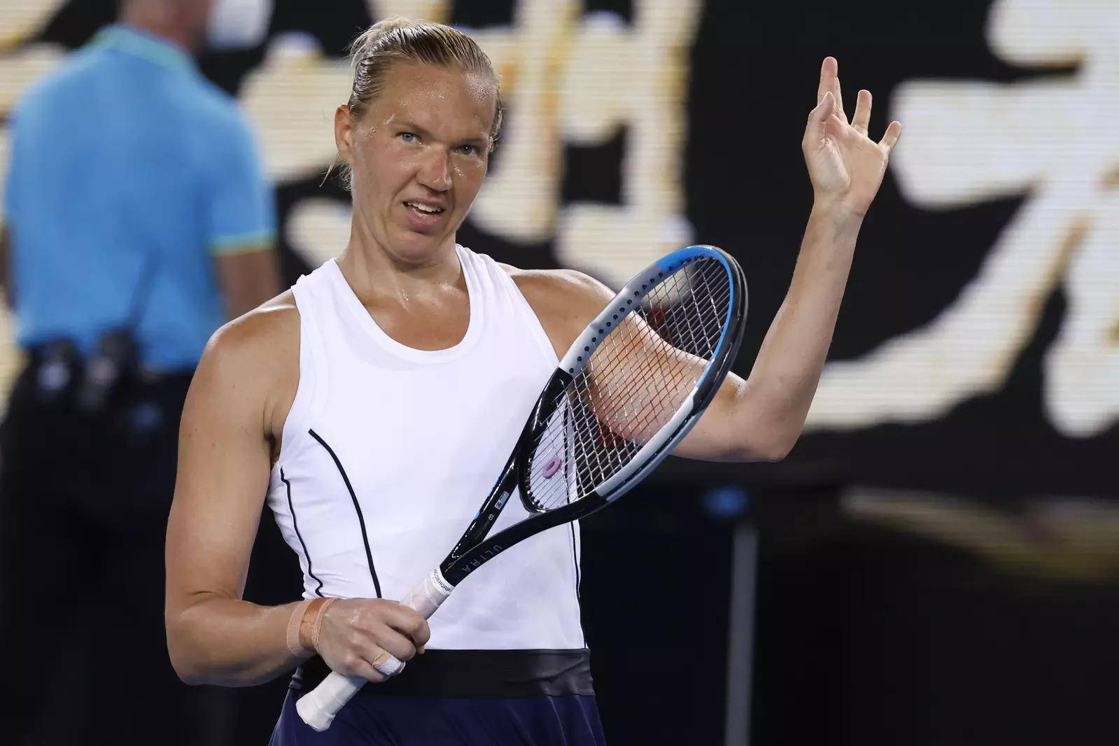 Tennis 桌布 壁紙 — 一位堅定的女網球運動員身穿白色背心，在比賽中緊握球拍，並用空著的手有力地做手勢。