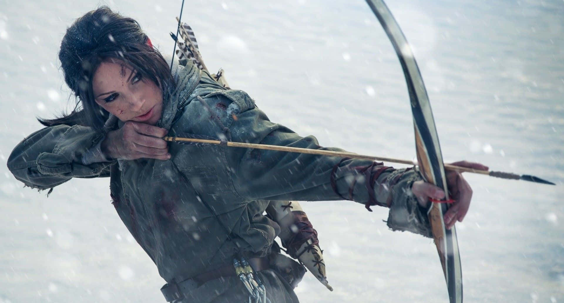 Lara Croft 桌布 壁紙 — 一位堅定的弓箭手穿著風化的裝備，在嚴冬的雪景中拉弓，雪花飄落。