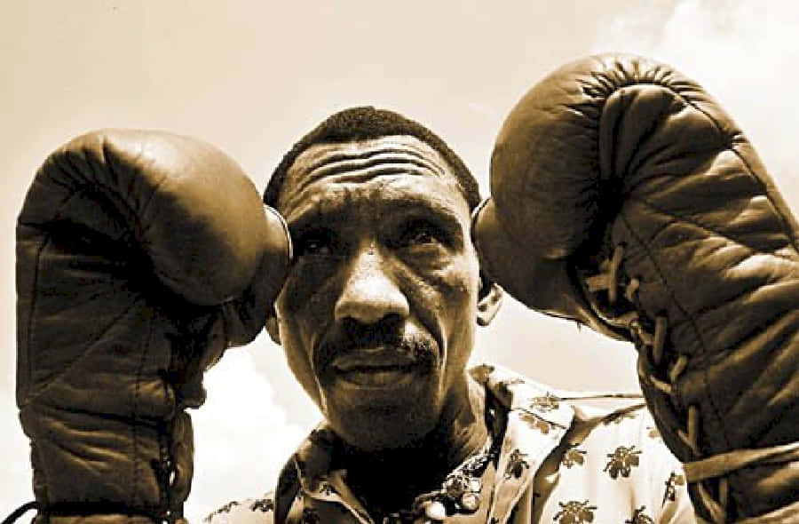 Boxing 桌布 壁紙 — 一位堅定的拳擊手戴著復古手套，拳頭高舉，對著明亮的天空凝視。