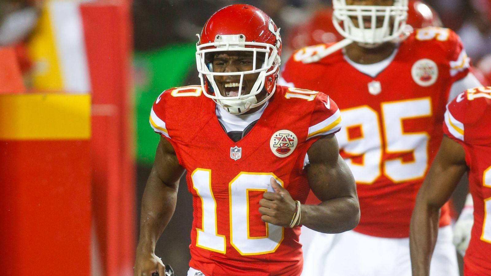 Tyreek Hill 桌布 壁紙 — 一位堪薩斯城酋長隊的美式足球員身穿紅色10號球衣，在體育場燈光下的夜間比賽中露出兇猛的笑容慶祝。