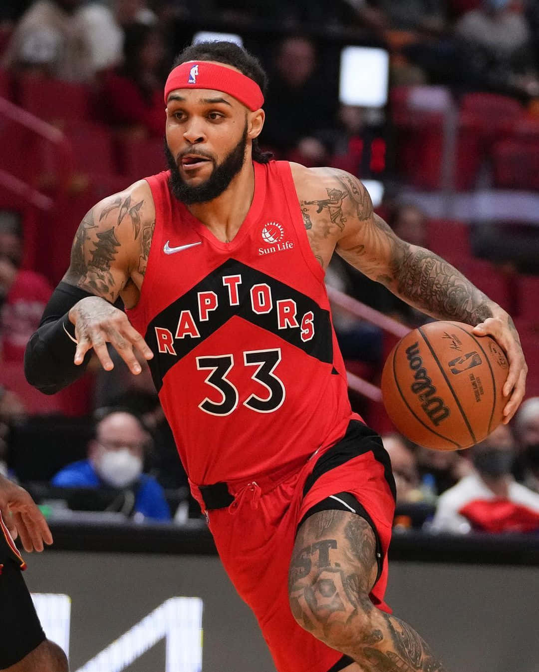 NBA 桌布 壁紙 — 一位多倫多暴龍隊籃球運動員身穿紅色球衣，在場館燈光下比賽中專注地運球。