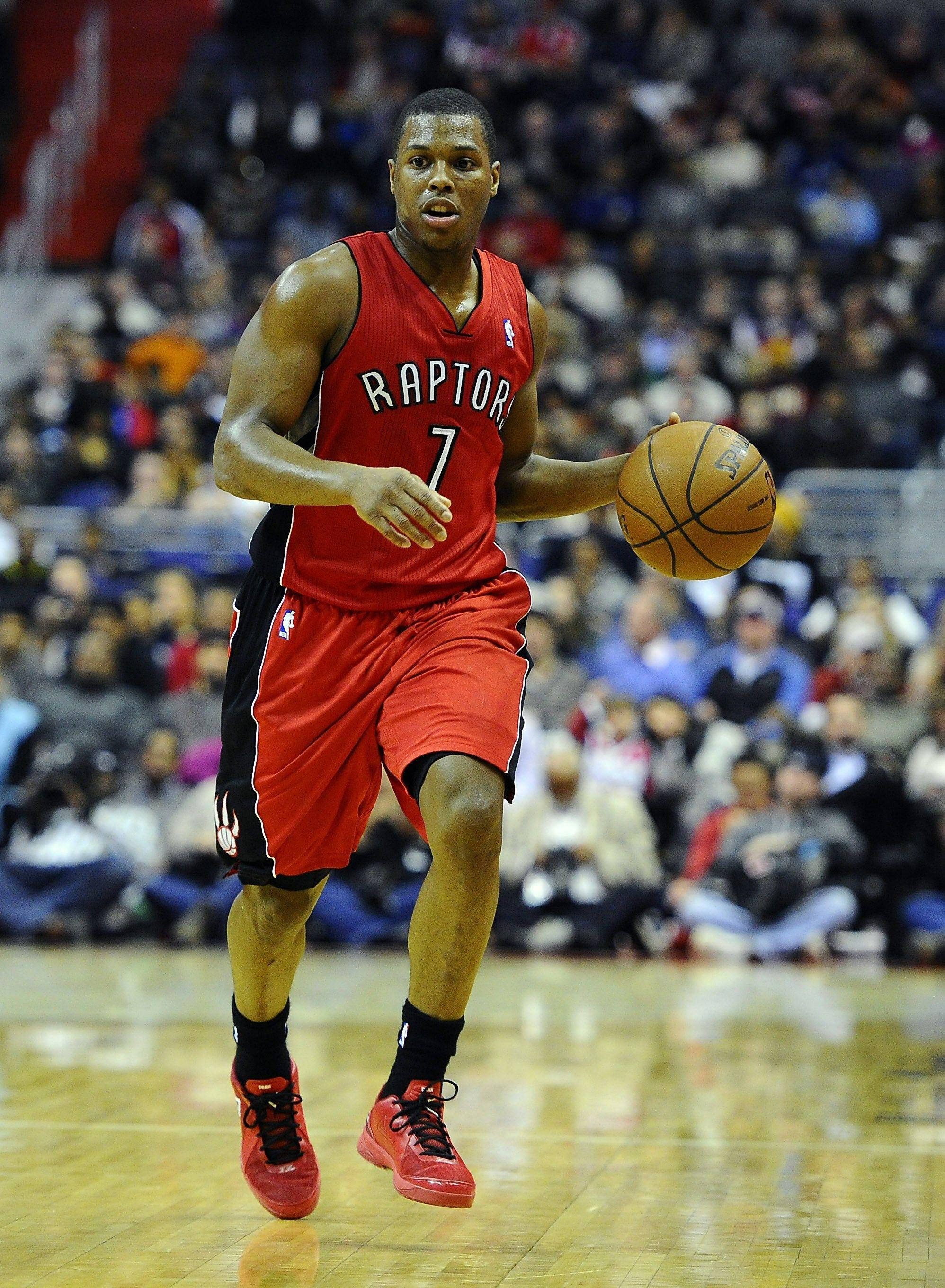 Lowry 桌布 壁紙 — 一位多倫多暴龍隊籃球運動員身穿紅色球衣，在激烈的比賽中運球，背景是模糊的人群。