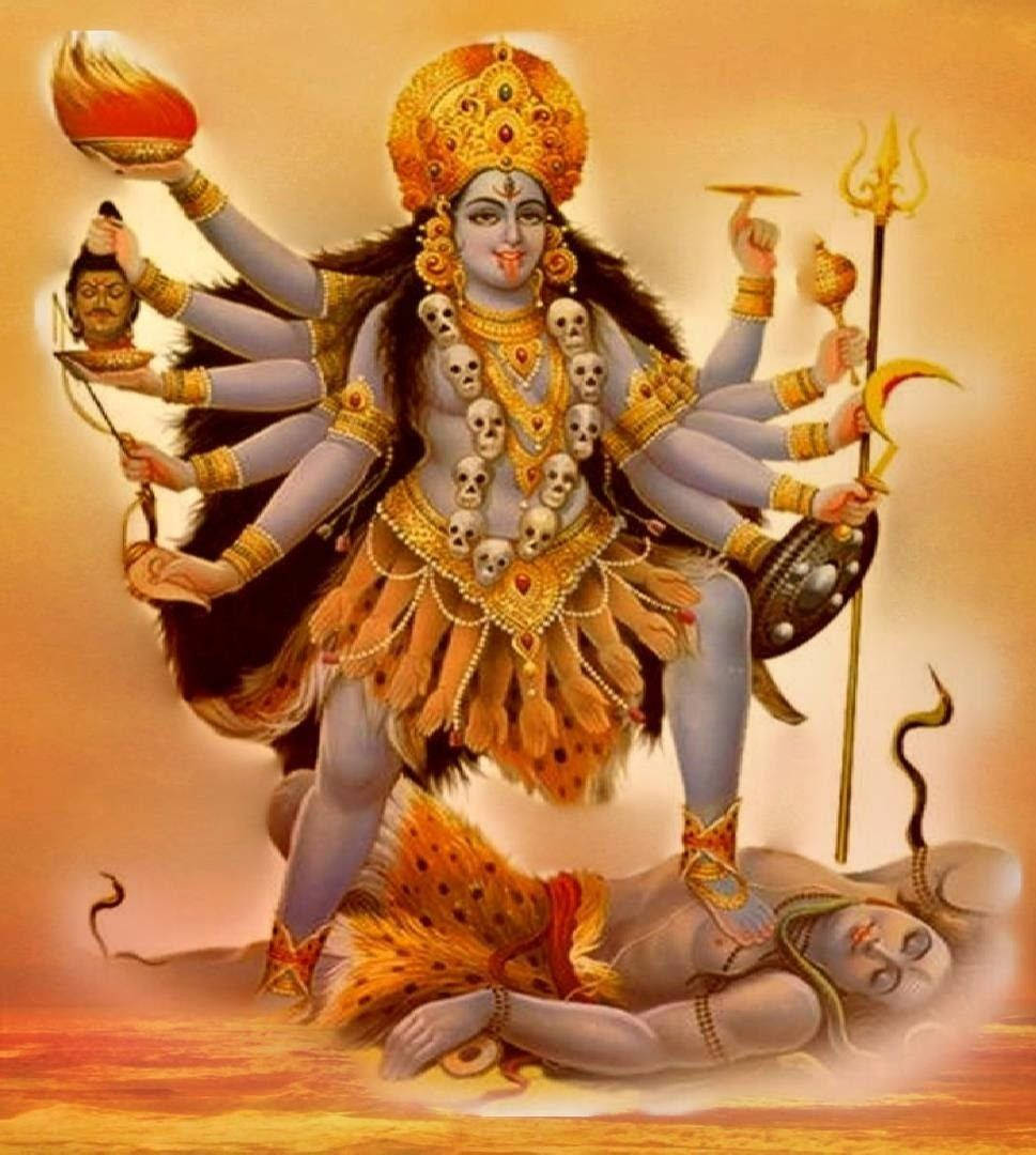 Hindu God 桌布 壁紙 — 一位多臂印度教女神，帶有頭骨和金色飾物，在溫暖發光的背景下勝利地站在被擊敗的惡魔之上。
