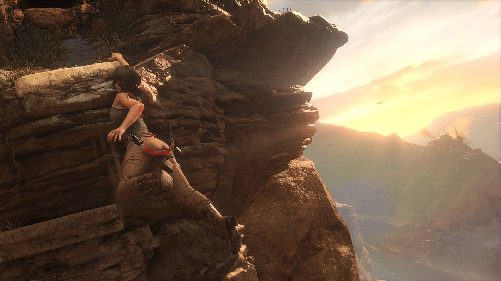 Rise Of The Tomb Raider 桌布 壁紙 — 一位女冒險家在日落時分攀爬崎嶇的懸崖，遠處的古老遺跡在金色光芒中閃耀。