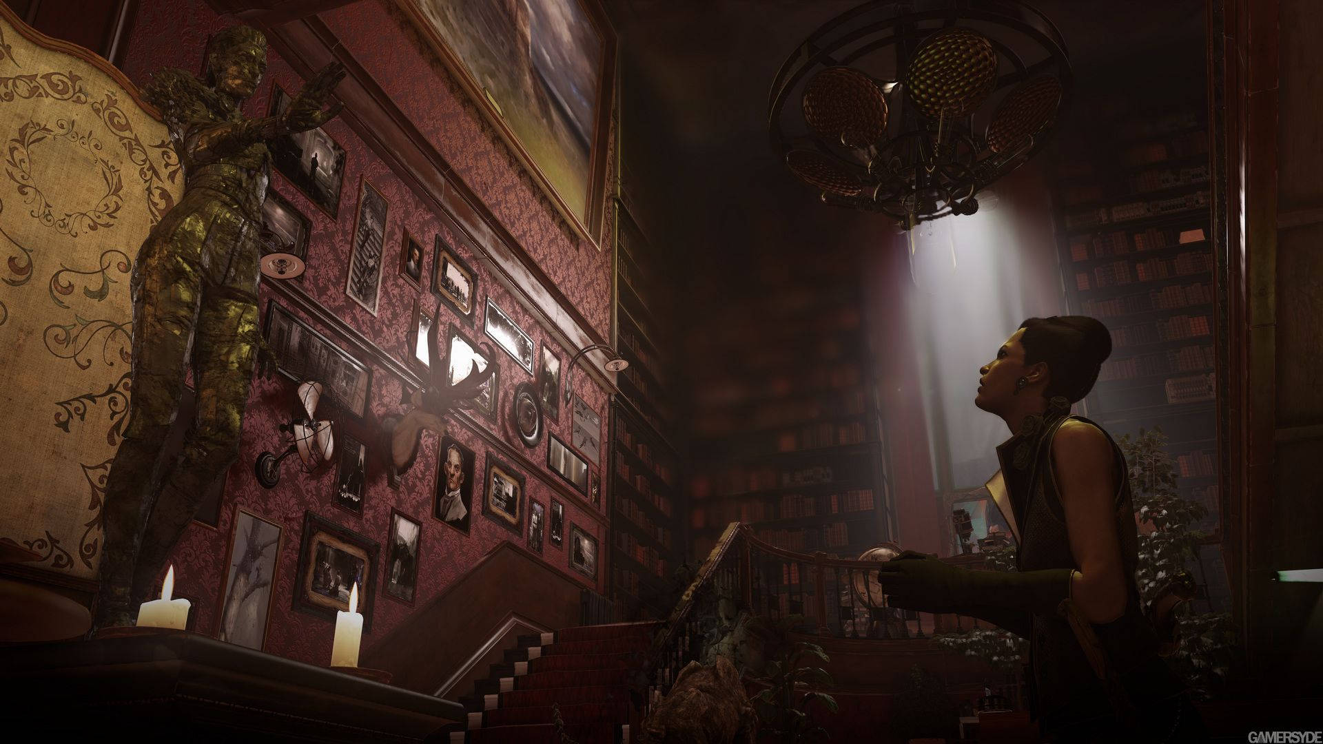 Dishonored 2 桌布 壁紙 — 一位女士在燈光昏暗、裝飾華麗的豪宅走廊中向上凝視，走廊上掛滿畫像，並有一座高聳的雕像矗立在吊燈下。