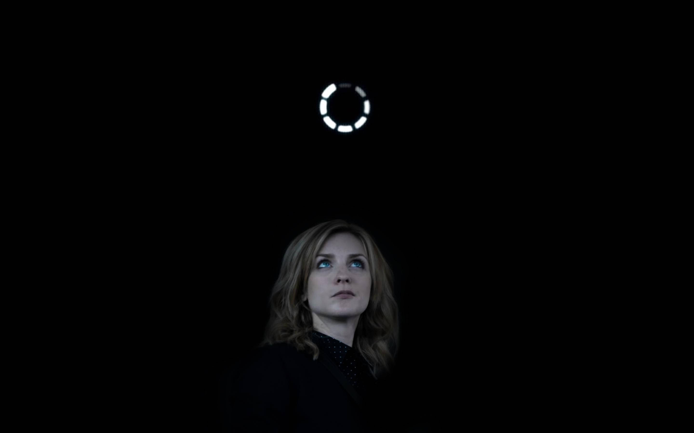 Netflix 桌布 壁紙 — 一位女士在黑暗中向上凝視頭頂上發光的圓形光線。