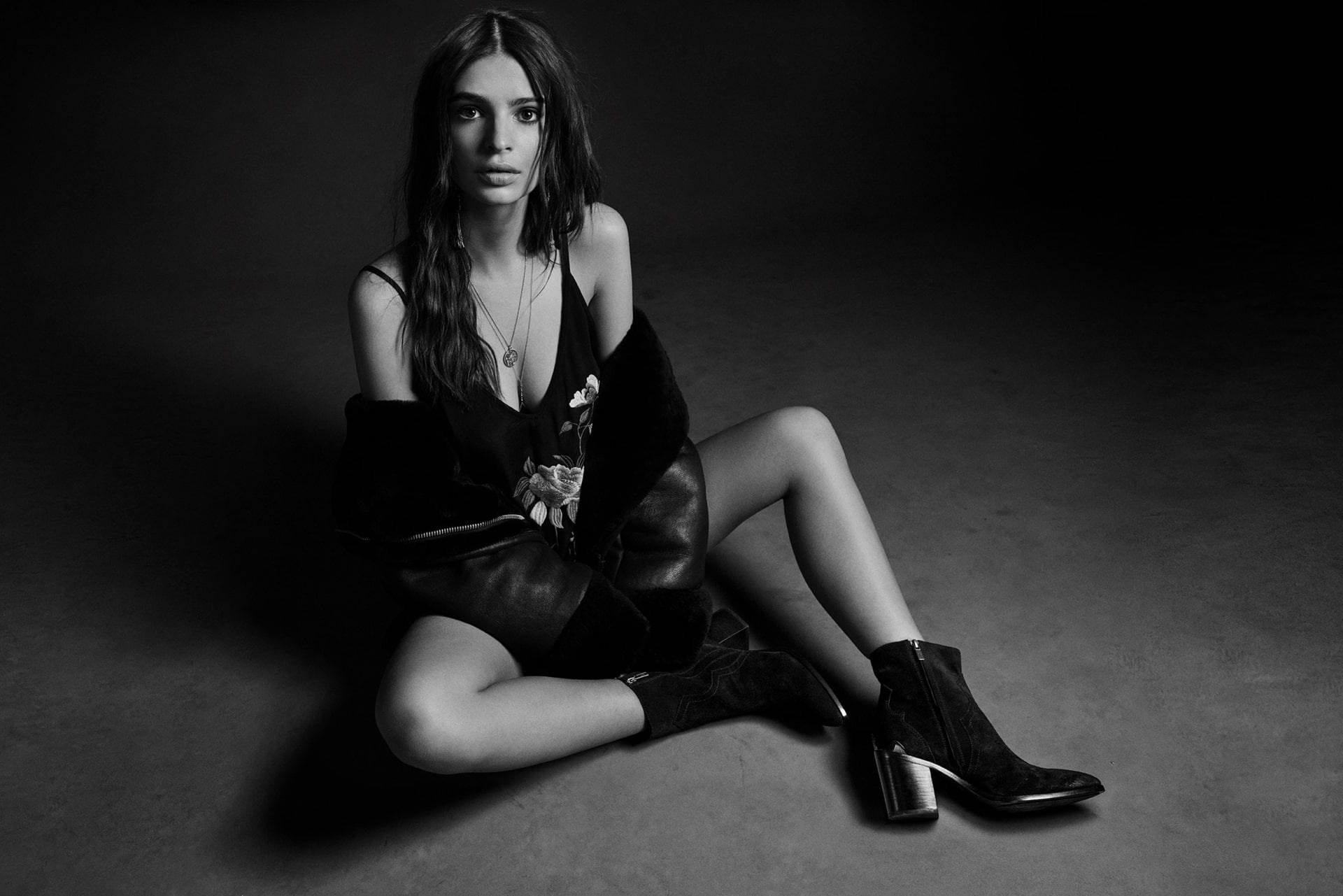 emily ratajkowski 桌布 壁紙 — 一位女士坐在深色地板上，黑白工作室肖像，戲劇性燈光，眼神強烈。