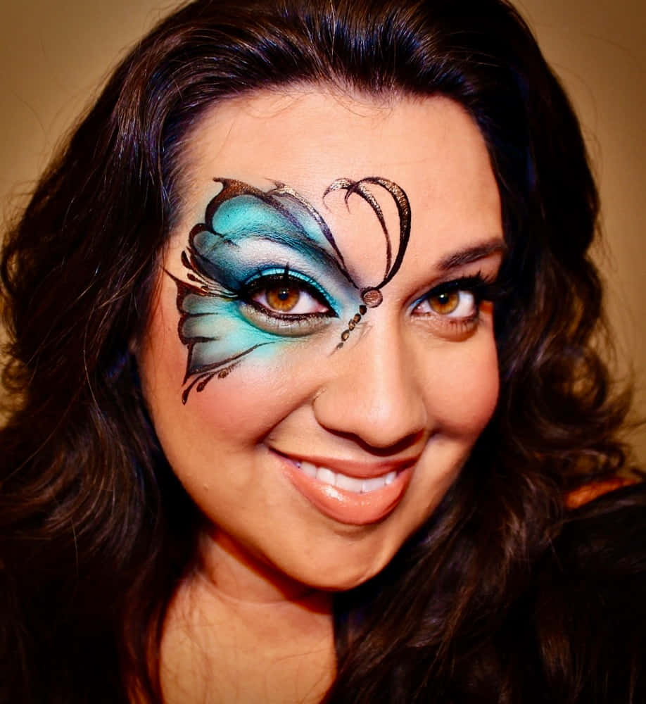 Butterfly Face Painting 桌布 壁紙 — 一位女士微笑，右臉頰和眼睛上有精緻的藍色和黑色蝴蝶化妝藝術。