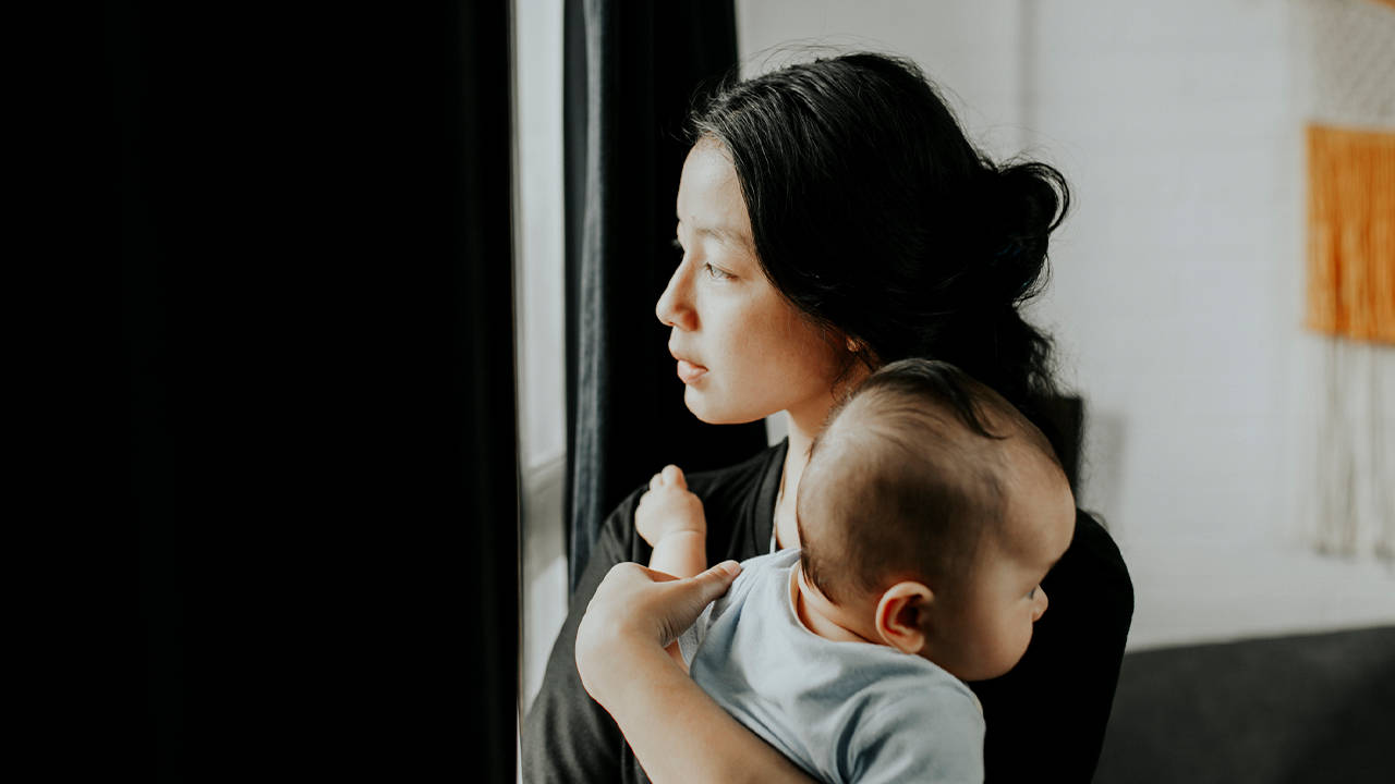 staring 桌布 壁紙 — 一位女士抱著嬰兒，在光線柔和的房間裡若有所思地望向窗外。
