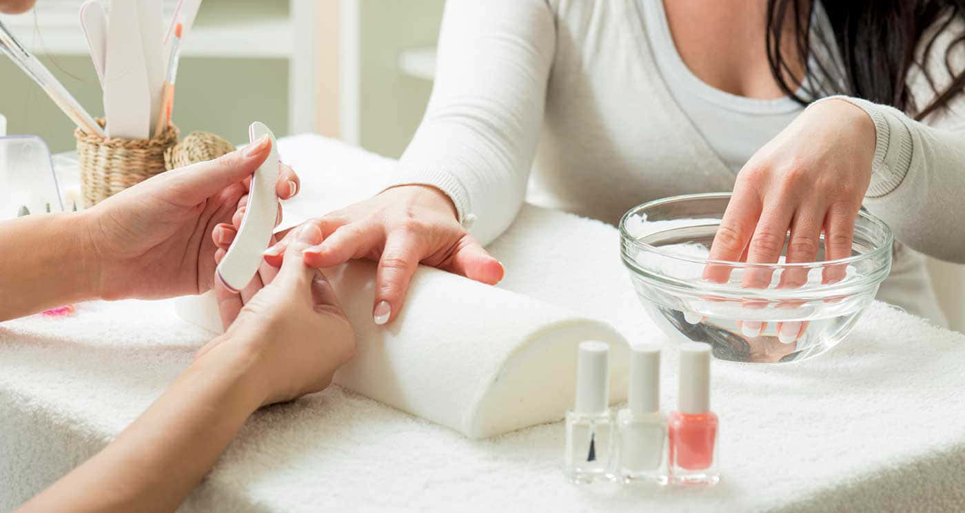 Manicure 桌布 壁紙 — 一位女士正在享受放鬆的美甲服務，她的手放在一碗水中，另一隻手正在為她銼指甲的特寫。