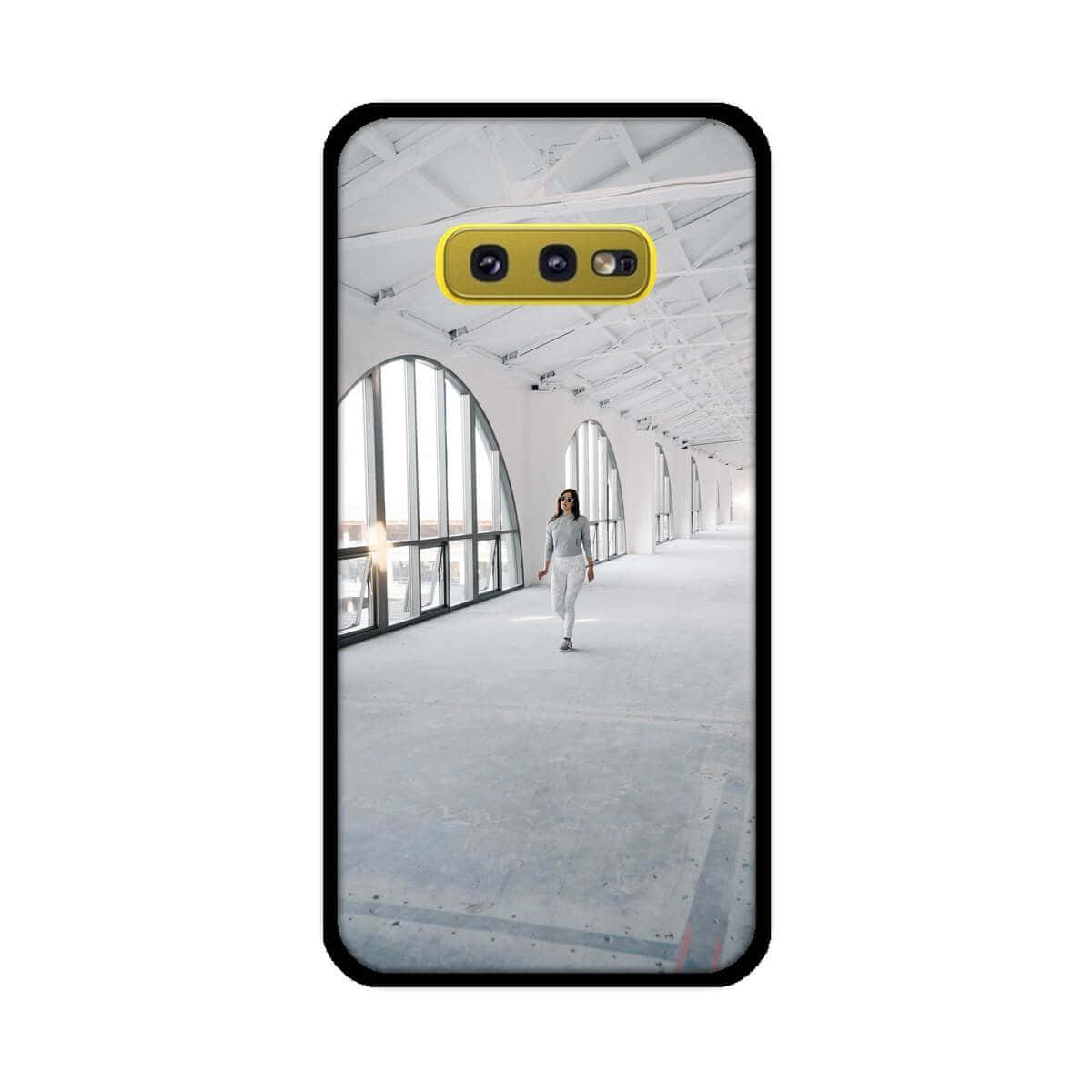 Galaxy S10 桌布 壁紙 — 一位女士獨自走過一條明亮的白色工業走廊，帶有拱形窗戶和裸露的橫樑。