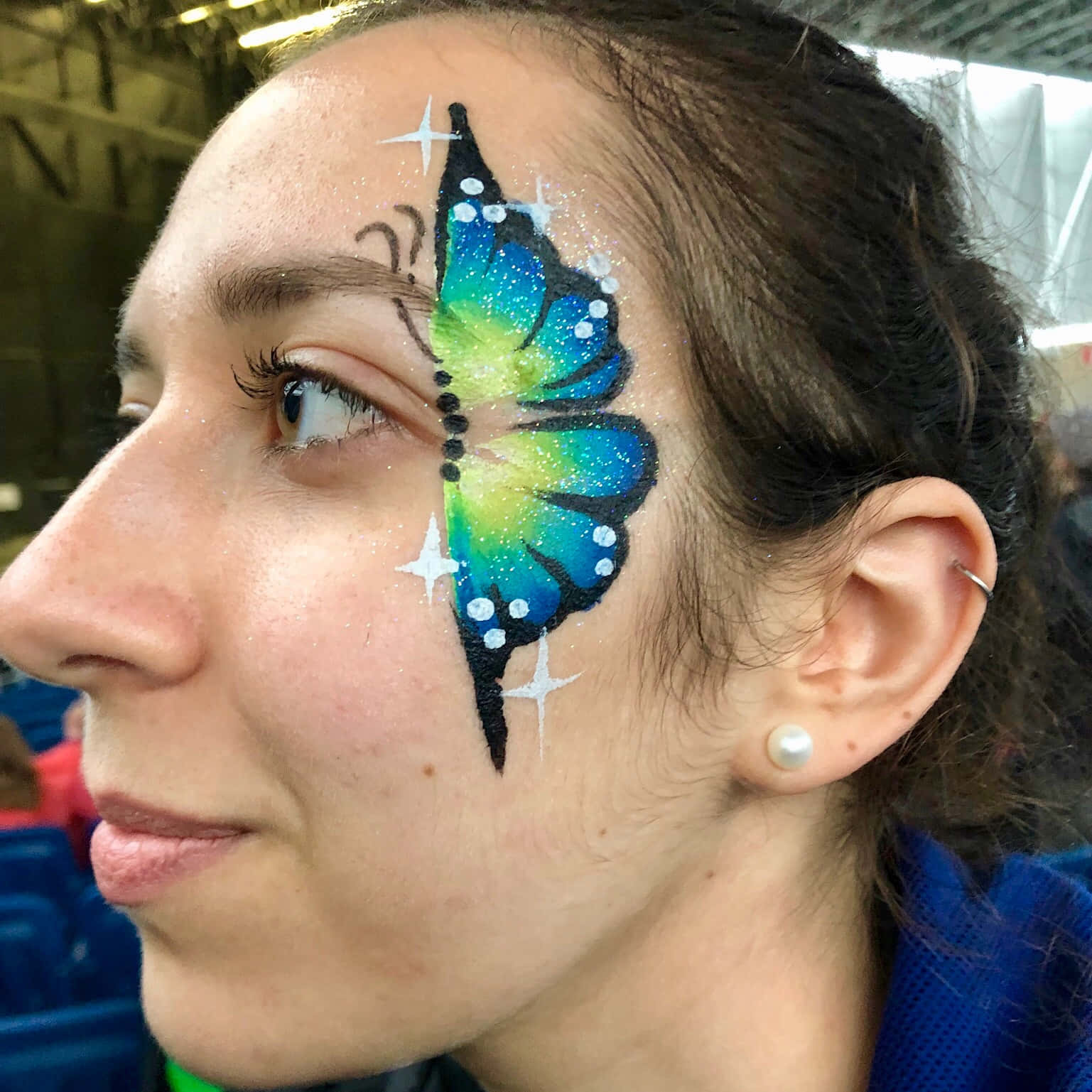 Butterfly Face Painting 桌布 壁紙 — 一位女士的臉龐，眼睛附近飾有充滿活力的藍色和綠色亮粉蝴蝶臉部彩繪設計。