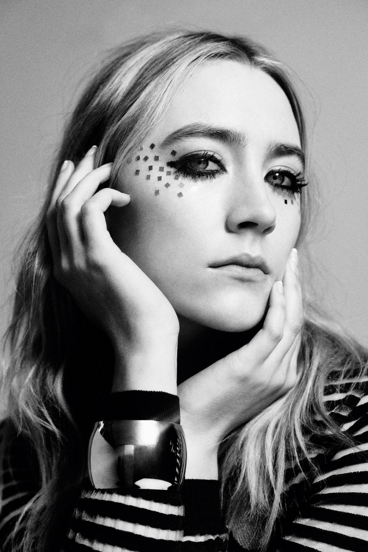 Saoirse Ronan 桌布 壁紙 — 一位女士的黑白肖像，帶有幾何面部彩繪，雙手框著她的臉。