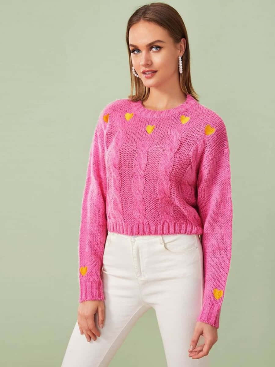 Pink Sweater 桌布 壁紙 — 一位女士穿著一件亮粉紅色絞花針織毛衣，上面有黃色心形貼花，背景是柔和的綠色攝影棚。