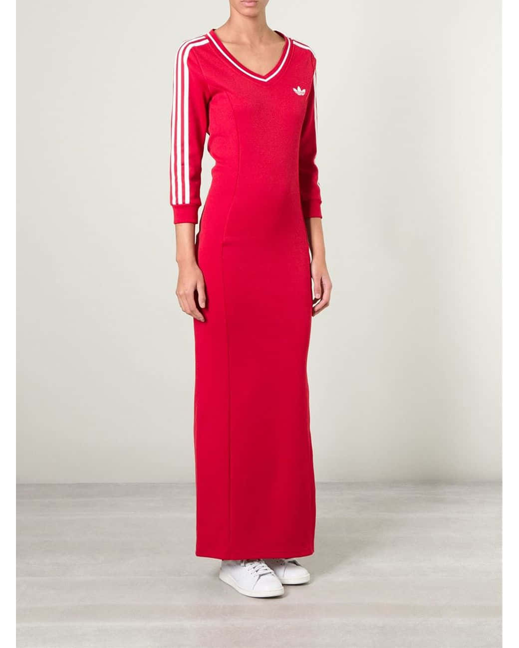 愛迪達 桌布 壁紙 — 一位女士站在攝影棚內，身穿鮮紅色Adidas運動套裝裙，搭配白色條紋和相配的運動鞋。