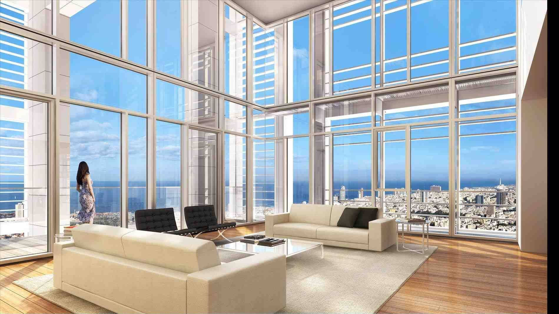 Apartment 桌布 壁紙 — 一位女士站在現代高層頂層公寓的落地窗旁，俯瞰著在晴朗藍天下延伸的城市和海洋。