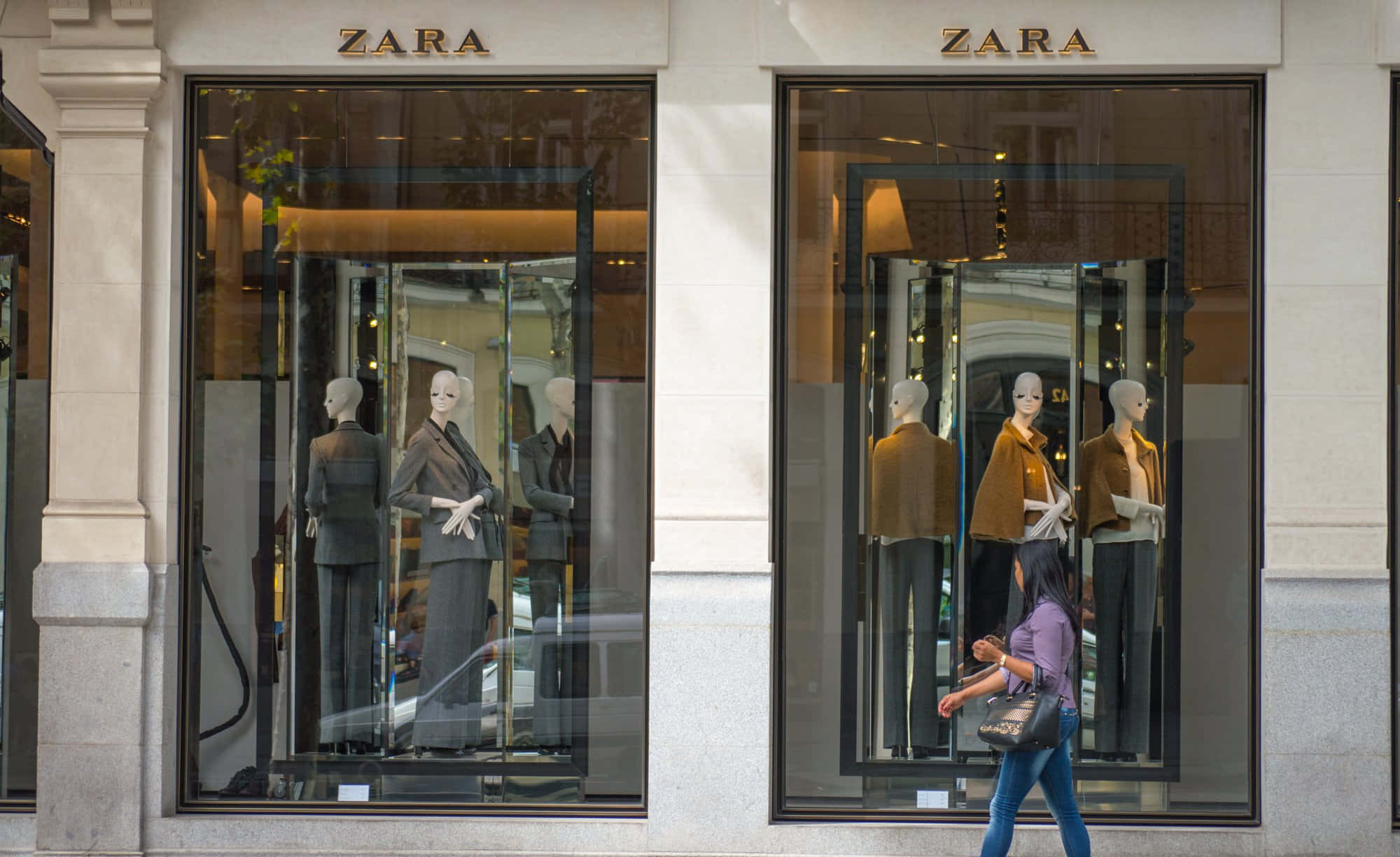 Zara 桌布 壁紙 — 一位女士走過兩個Zara商店櫥窗，櫥窗內展示穿著訂製西裝和外套的人體模型。
